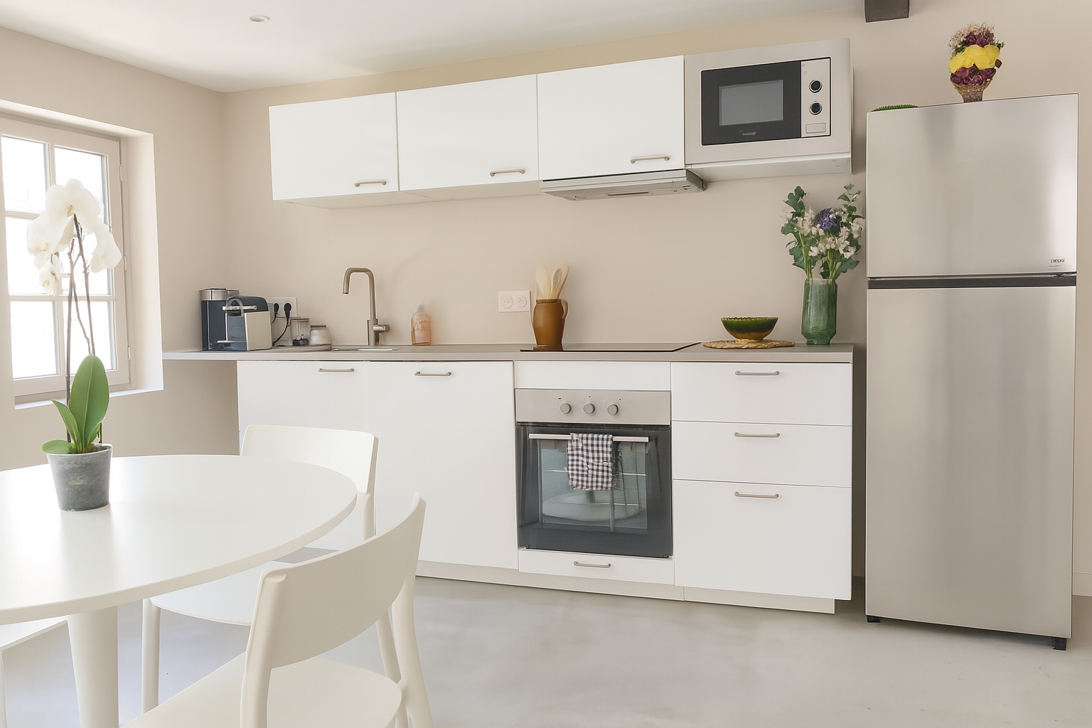 Modern kitchen with a white countertop, oven, refrigerator, microwave, plants, and dishes