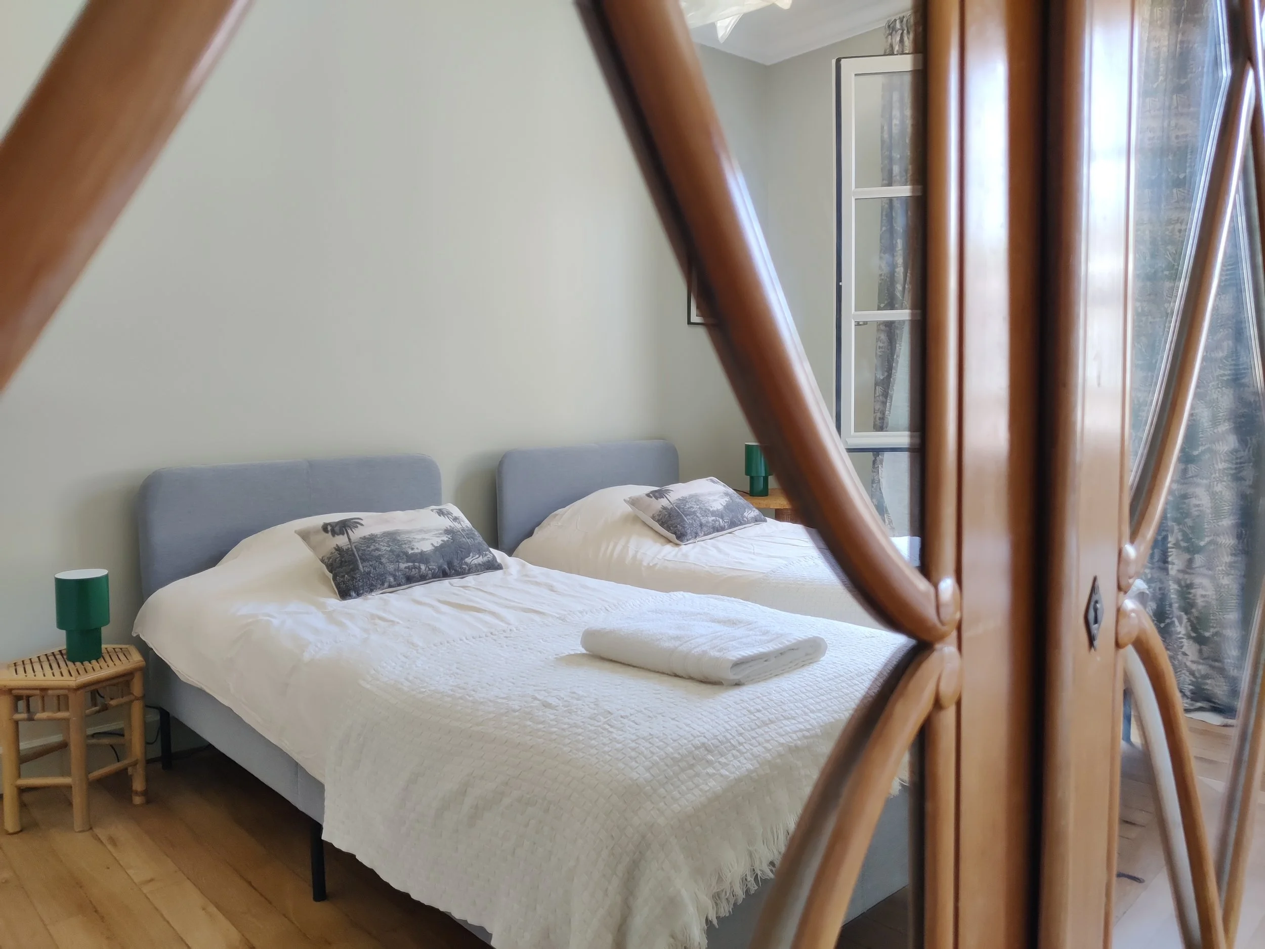 Room with two beds, patterned pillows, and towels on each bed
