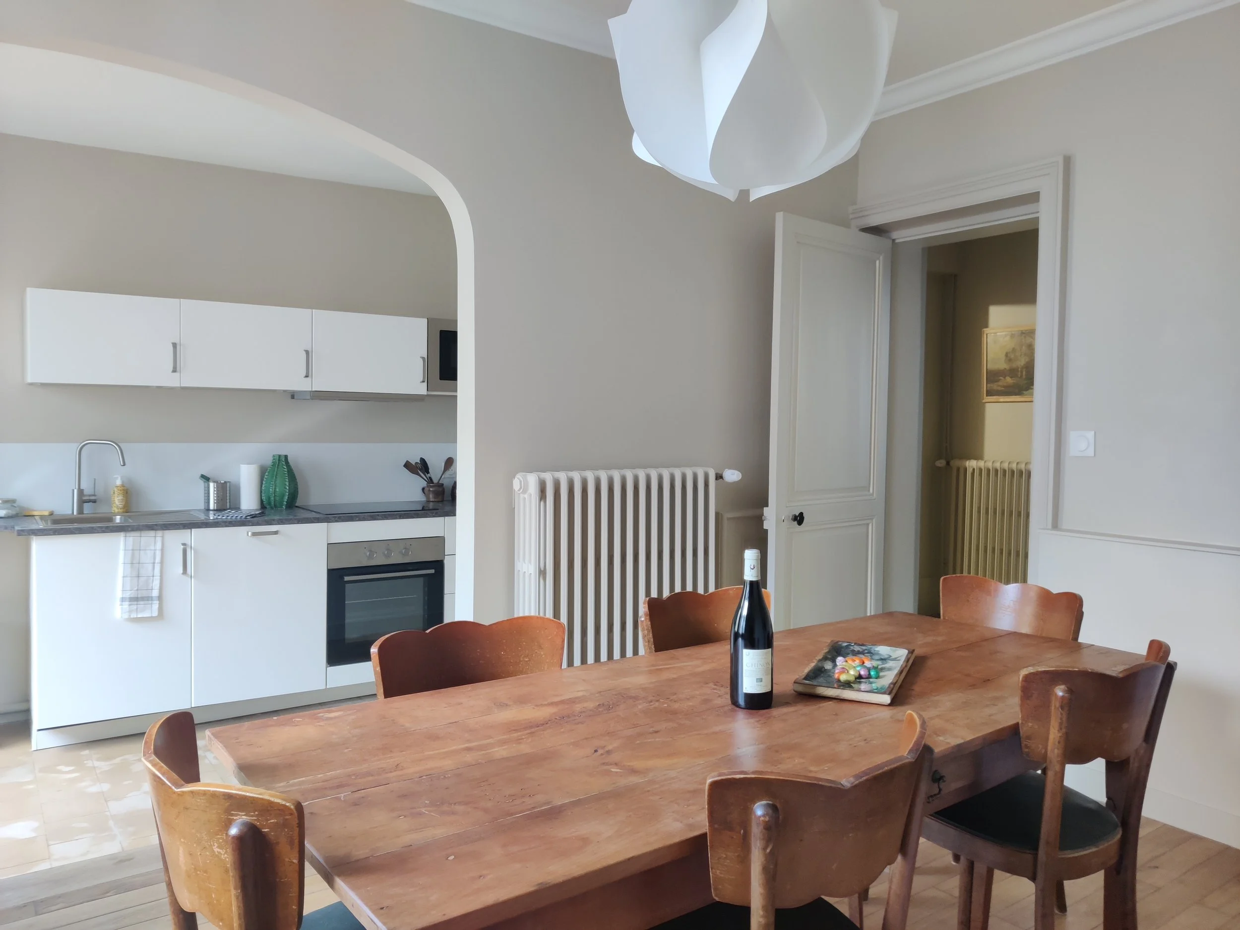 Dining room, wooden table, wooden chairs, wine, fully equipped kitchen in the background
