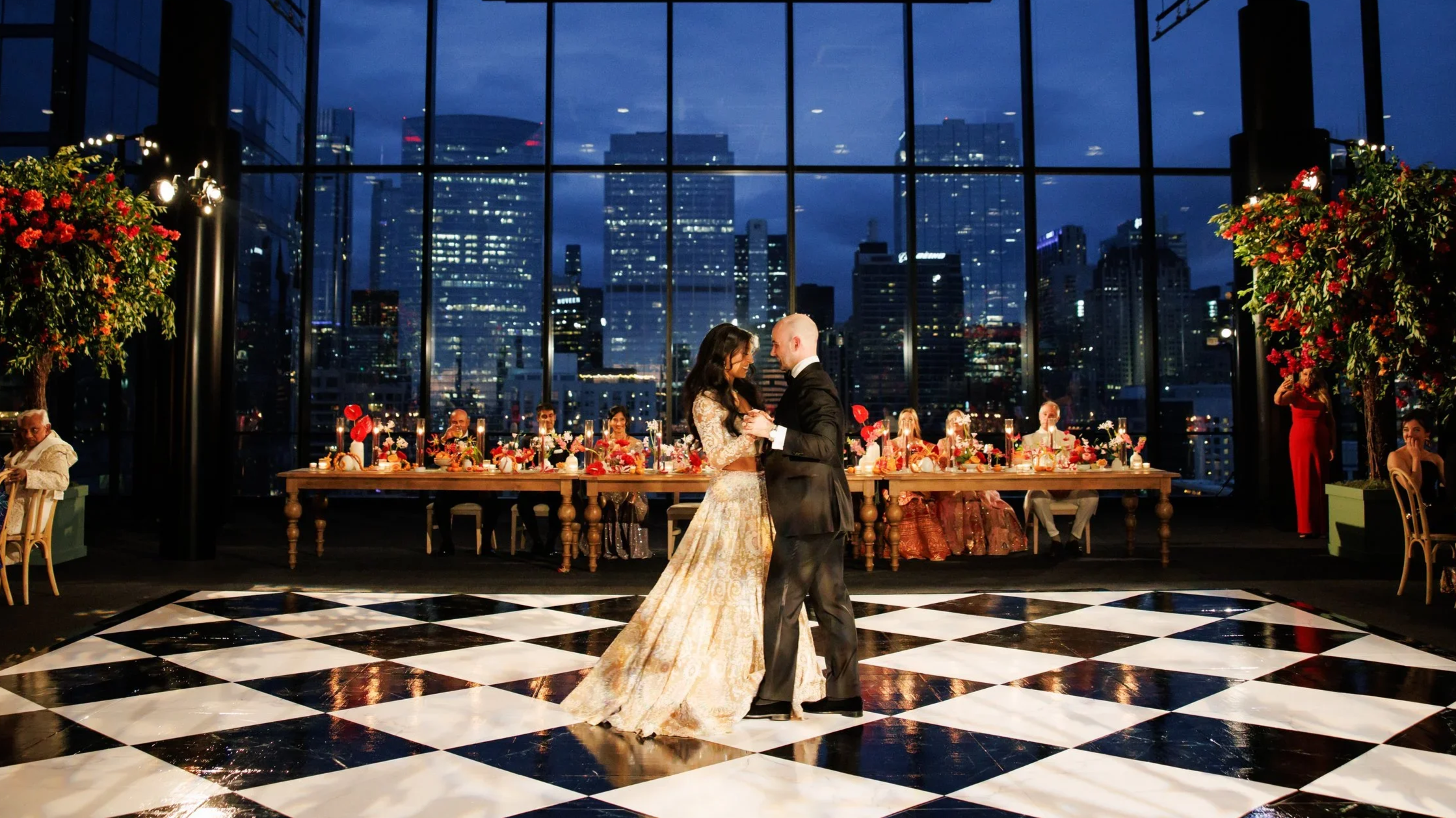 Bride and groom dancing their first dance on a black and white custom dance floor with their head table and downtown Chicago behind them