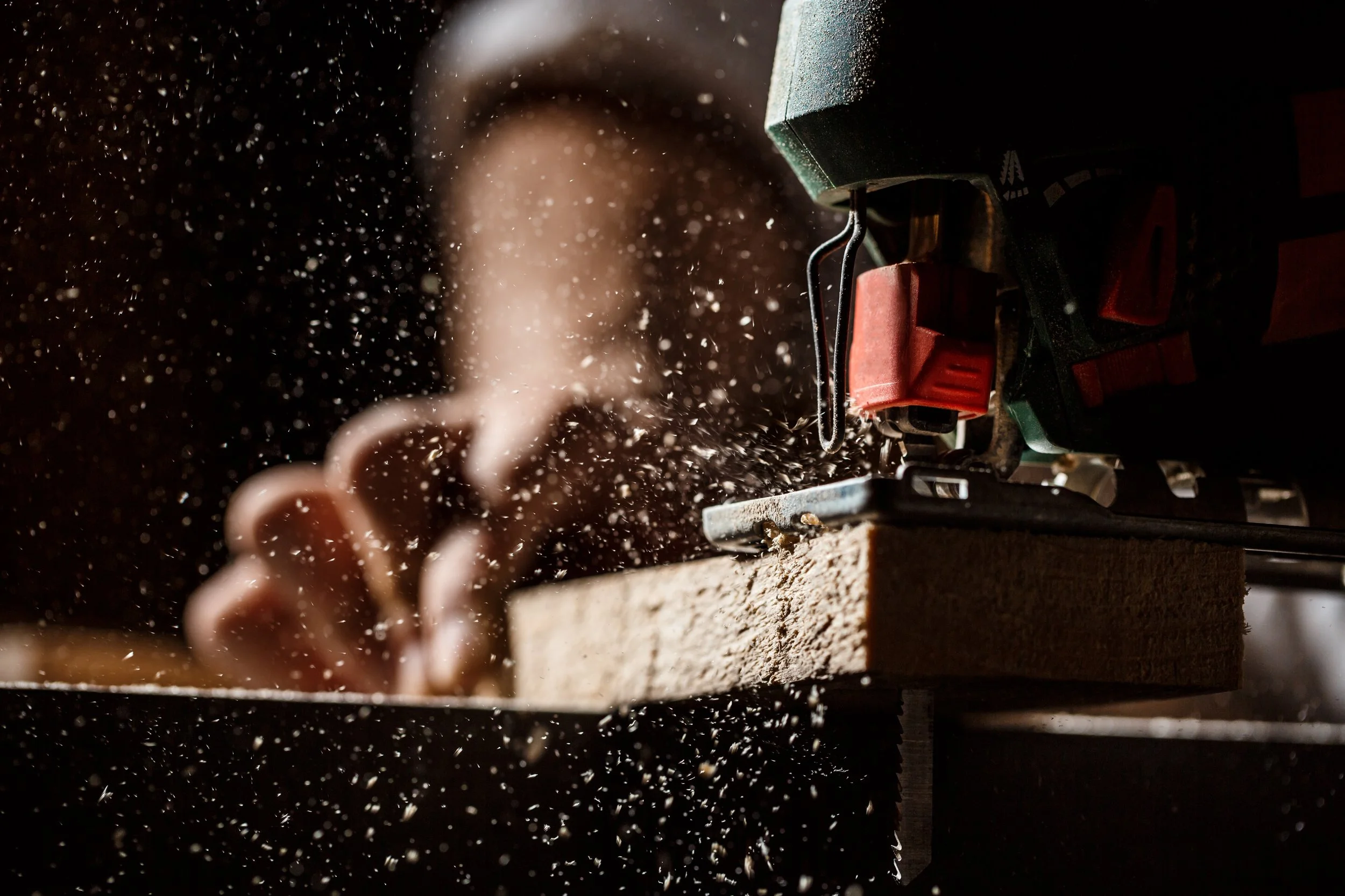 Persona che lavora con una sega circolare, con polvere di legno in volo.