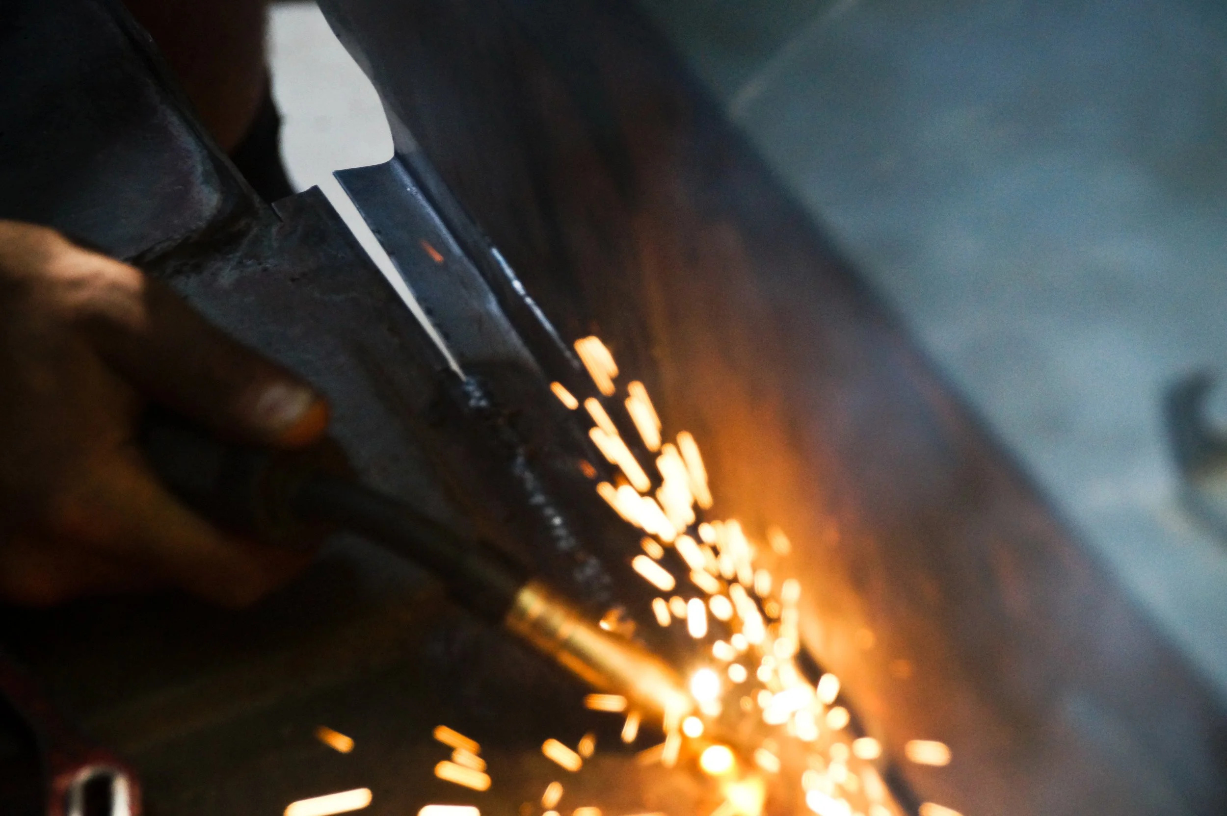 Lavoratore che taglia il metallo con una smerigliatrice, creando scintille.