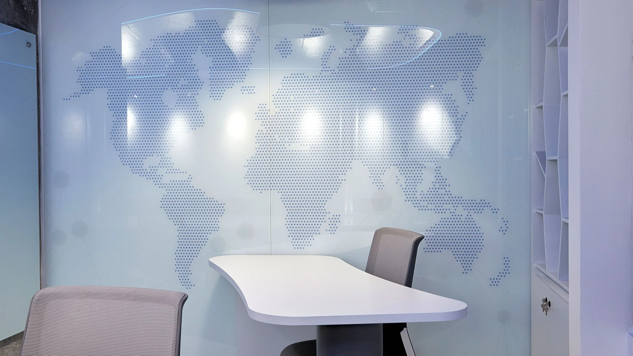 Mapa del mundo en una pared de oficina con mesa y sillas cercanas.