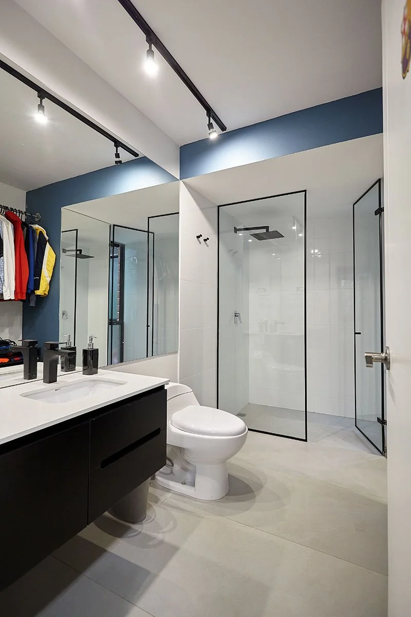 Baño moderno con lavabo, inodoro y ducha con puerta de vidrio.