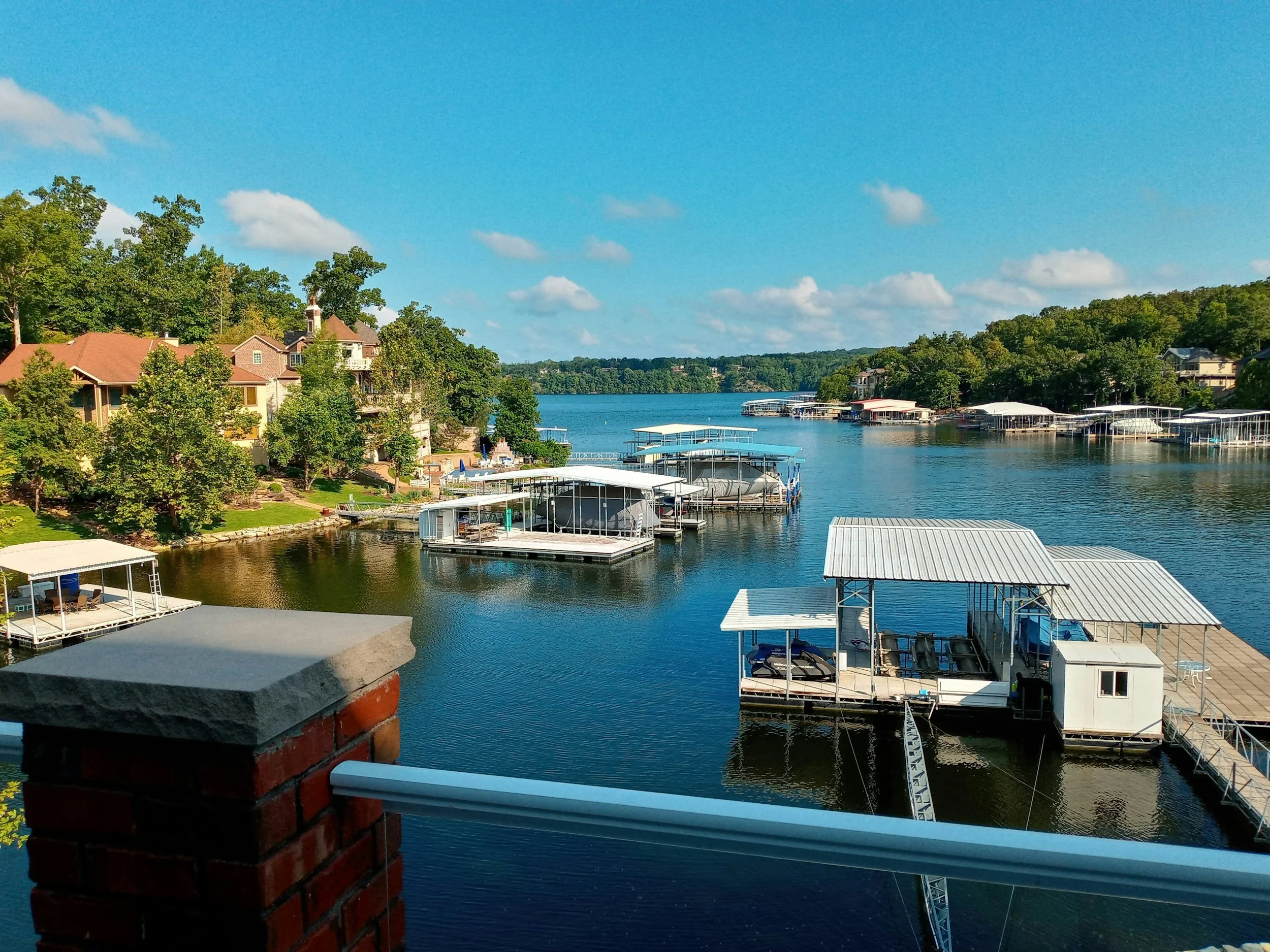 A scenic view of a lake with houses and boat docks along the shoreline on a clear, sunny day.