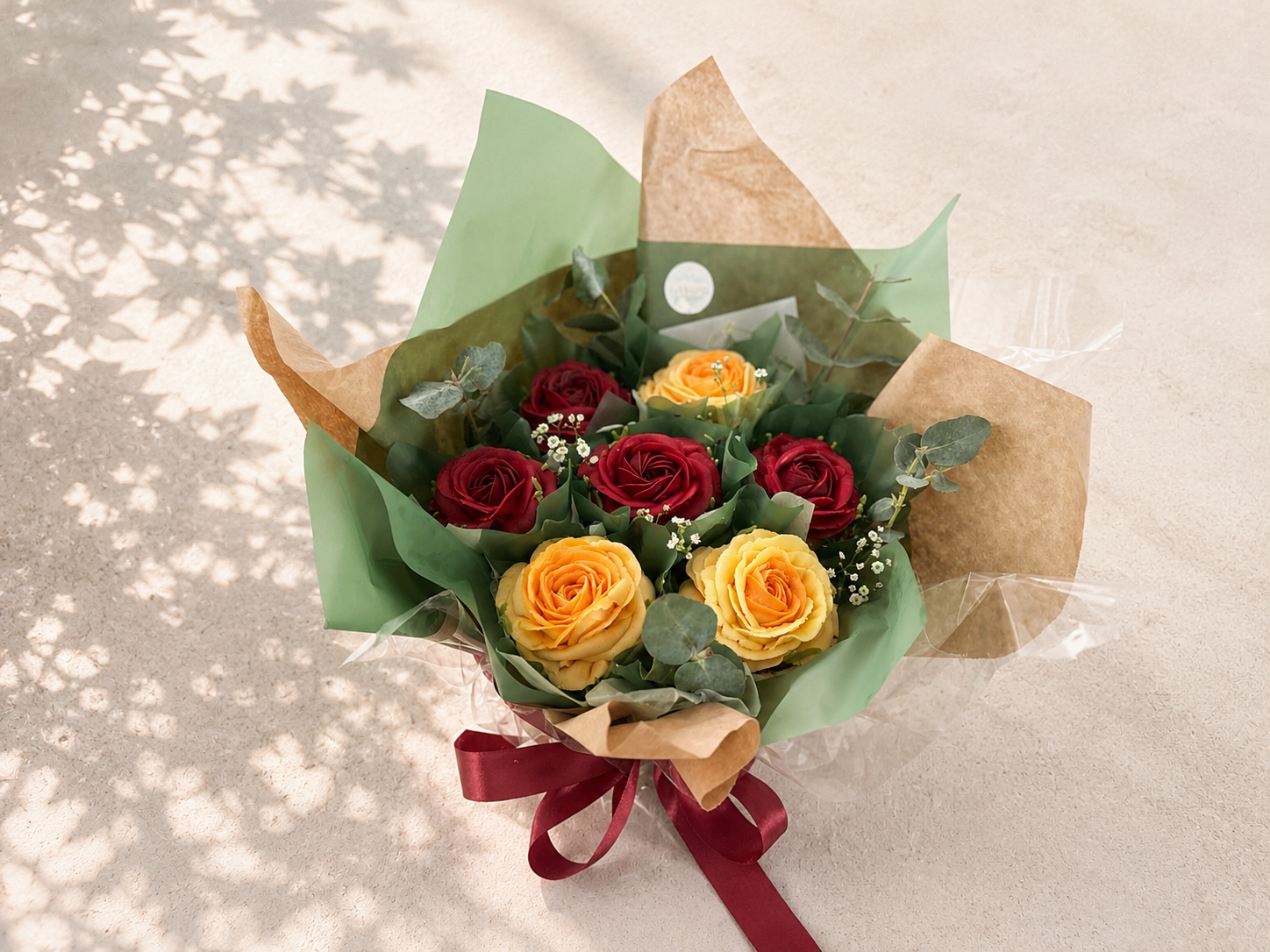 Seven cupcake rose bouquet featuring hand-piped deep red and yellow buttercream roses, wrapped in kraft and green paper and handcrafted in Dublin by Full Bloom Bakehouse. A luxury cupcake bouquet inspired by classic rose arrangements, perfect for bir