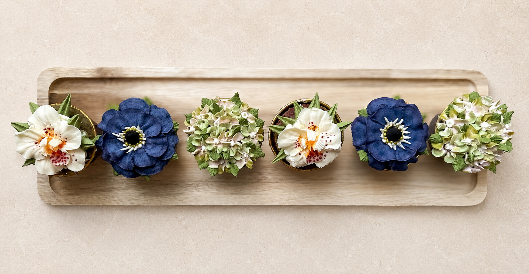 Hand-piped dark blue anemones and white orchid cupcakes, handcrafted in Dublin by Full Bloom Bakehouse. An elegant floral cupcake collection ideal for men, weddings, corporate events, client gifting and thank you gifts. Luxury buttercream flower cupc
