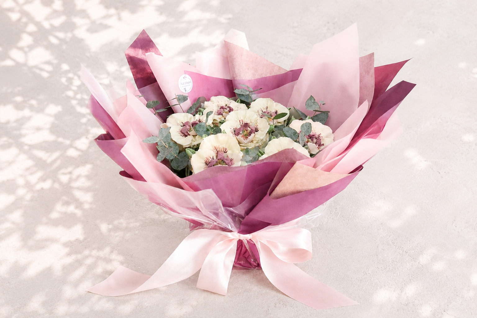 Hand-piped white orchid cupcake bouquet wrapped in deep pink paper, handcrafted in Dublin by Full Bloom Bakehouse. An elegant floral cupcake bouquet and luxury edible gift, perfect for birthdays, anniversaries, Mother’s Day, thank you gifts and speci