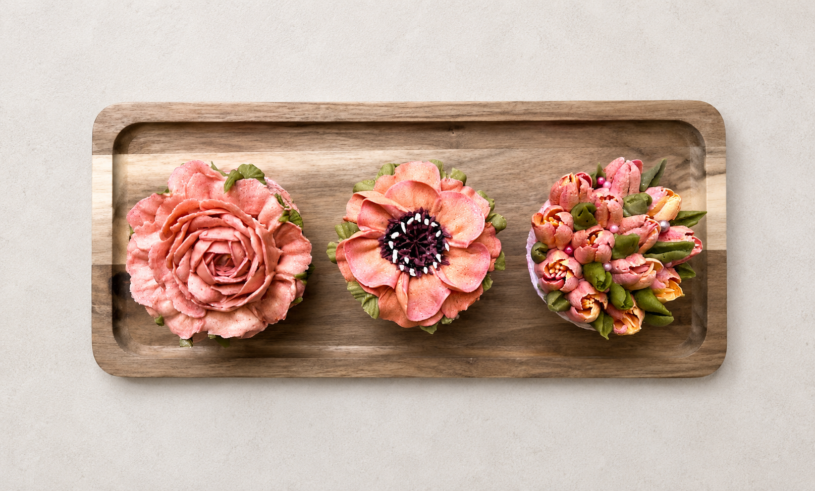 Hand-piped pink floral cupcakes featuring roses, poppies and tulips, handcrafted in Dublin by Full Bloom Bakehouse. Perfect for a girl's birthday party, baby shower or special celebration. Luxury floral cupcakes with realistic buttercream flowers ava