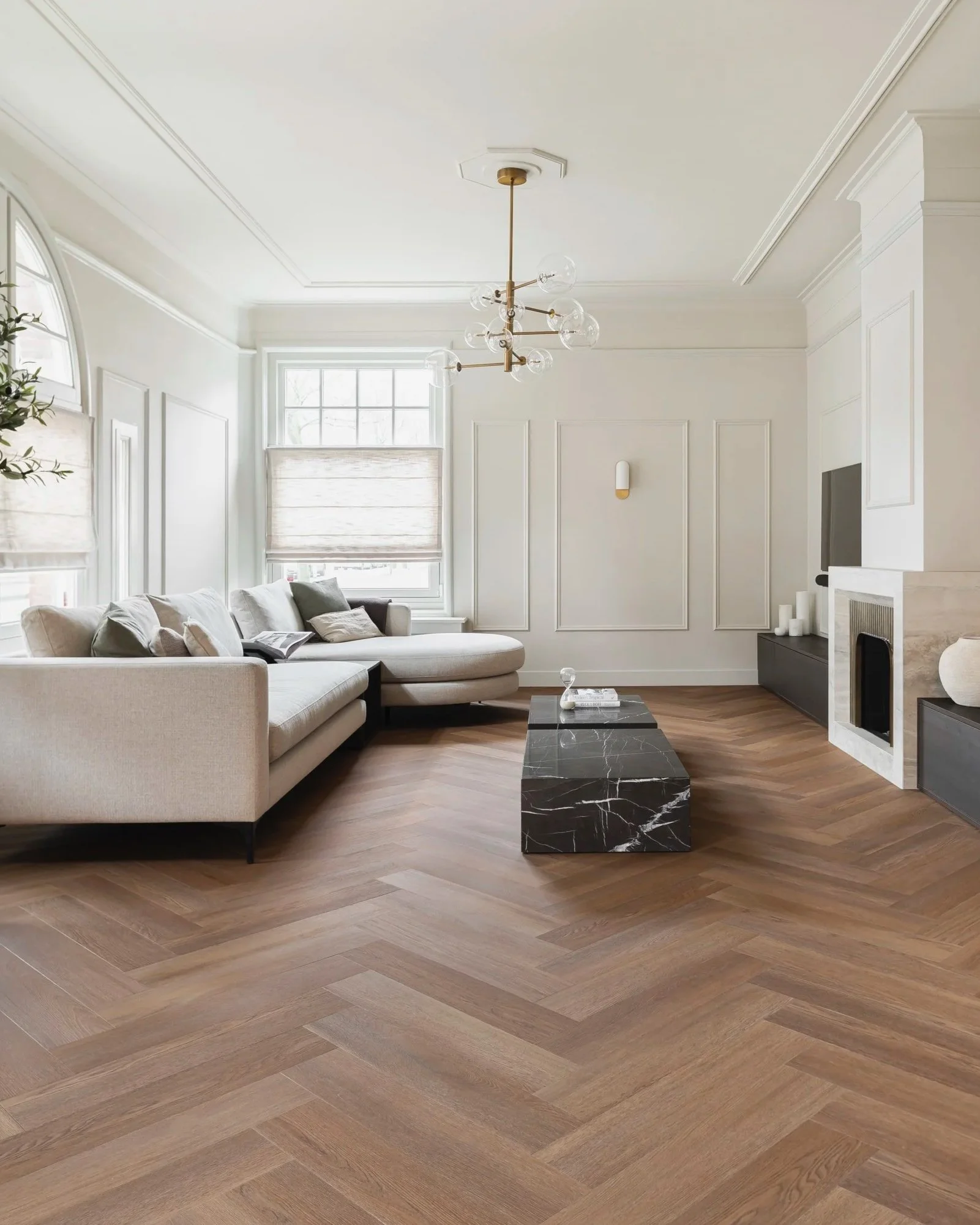 Modern living room with beige sectional sofa, black marble coffee table, and white walls with decorative wall panels.