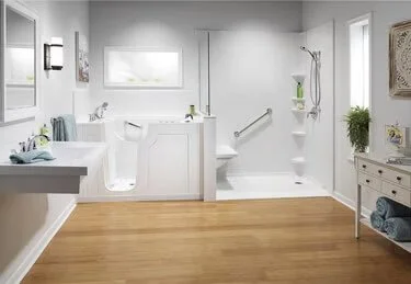 Bright bathroom with white fixtures, a bathtub, walk-in shower, and wooden flooring.