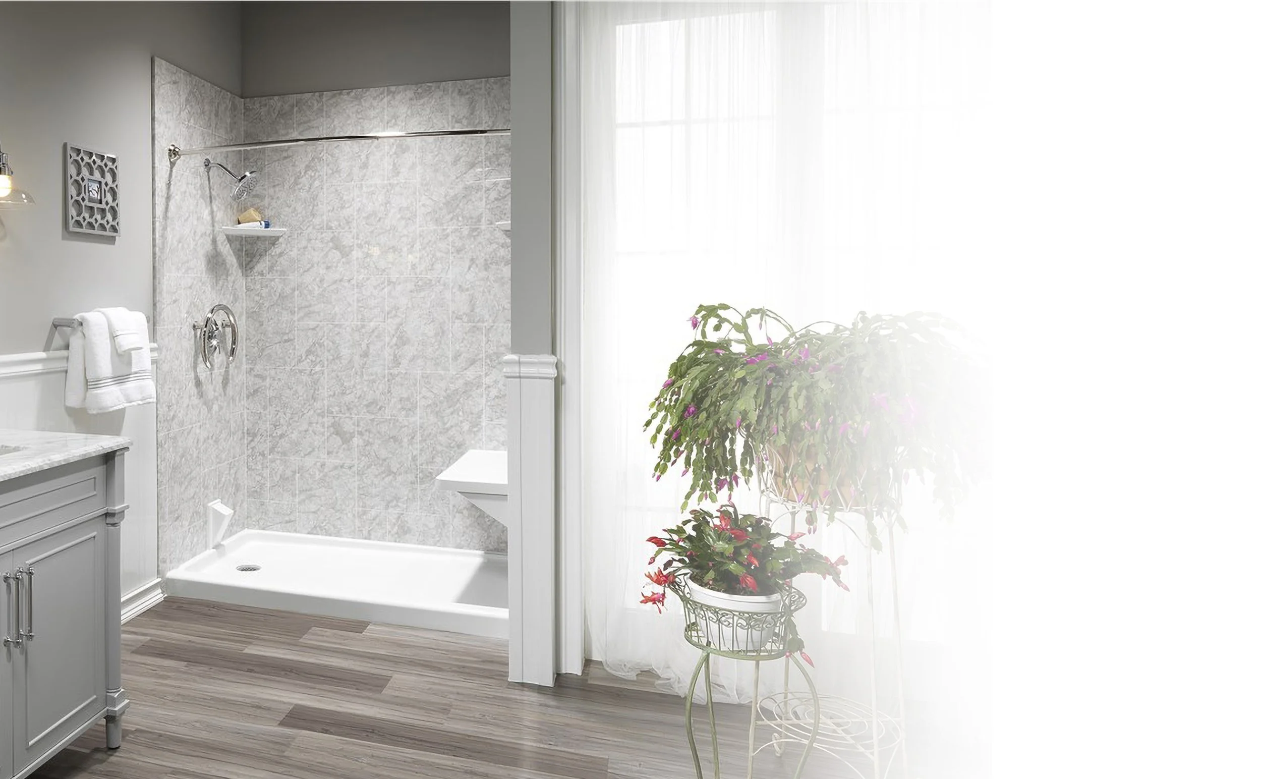 A bathroom with a walk-in shower, white vanity, and potted plants by a sheer curtain on a window.