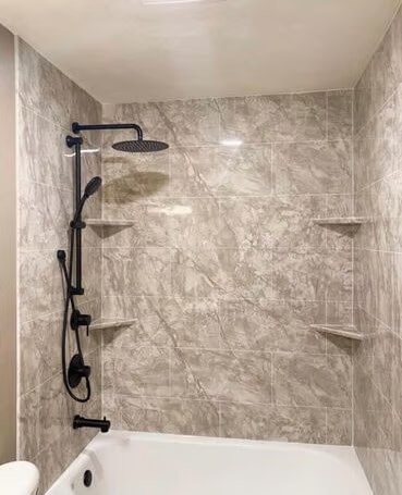 Shower area with a rain shower head, a handheld shower head, and three corner shelves on a tiled wall.