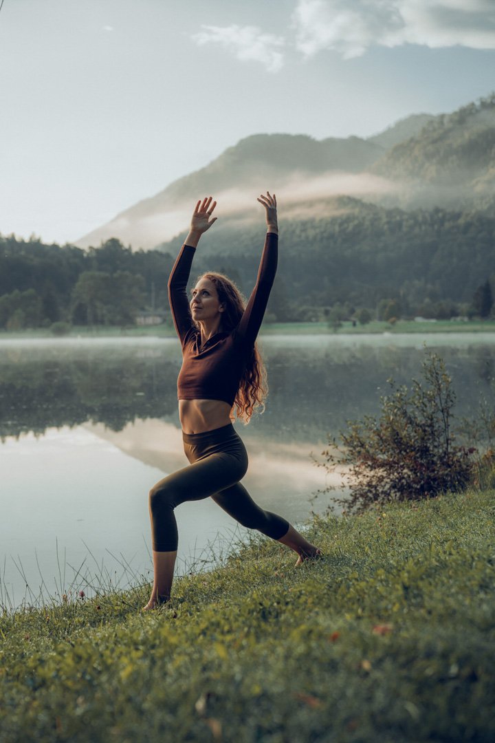 Frau beim Yoga am See bei Morgenlicht.