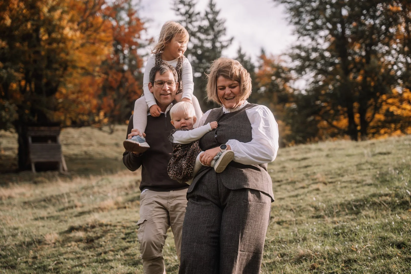 Familie mit zwei Kindern beim Spazieren im Herbst, lachend und miteinander spielend
