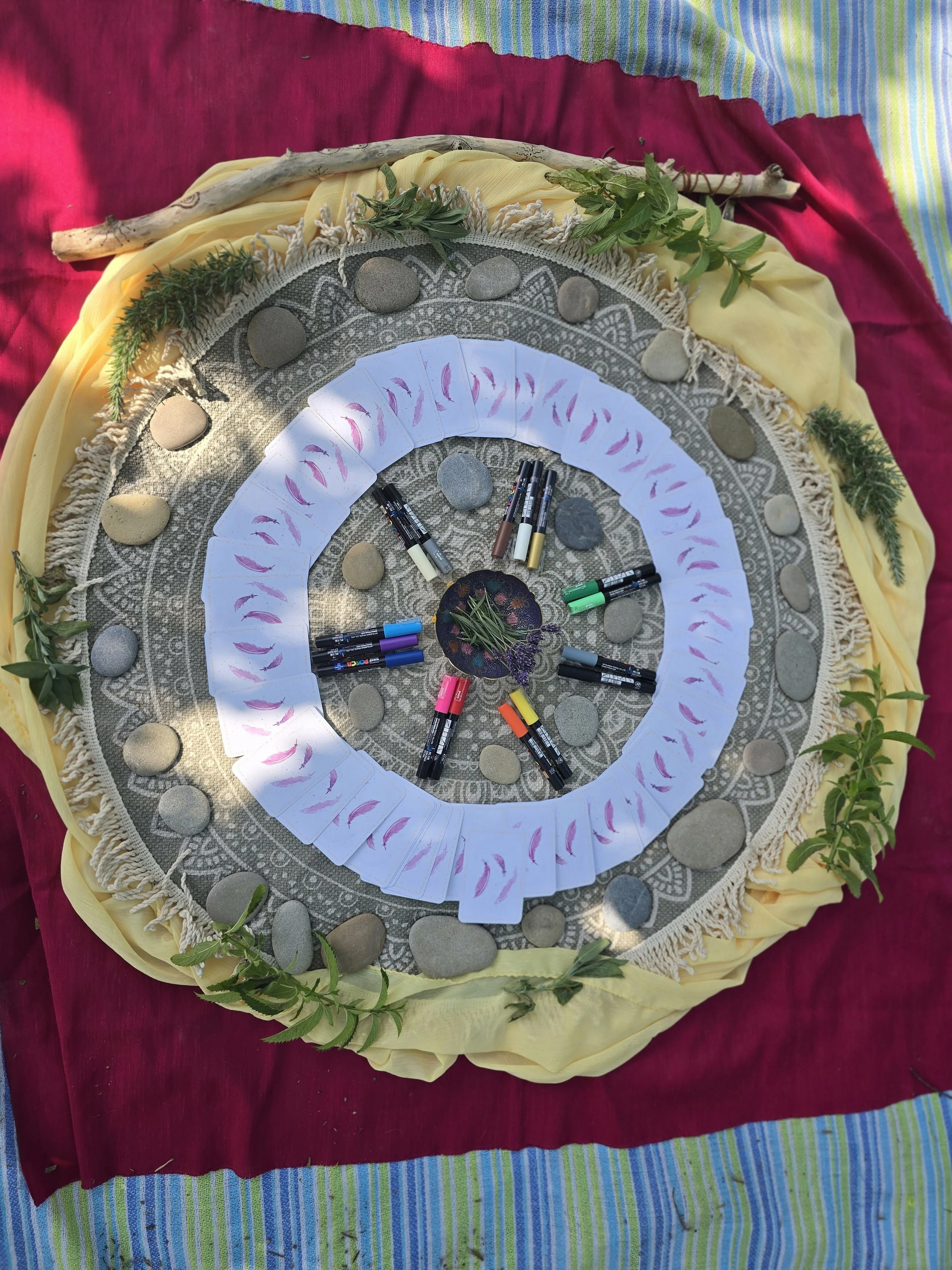 Ein runder Countdown mit Karten, bunten Markern, Steinen, Blättern und Blüten auf einer bunten Stoffunterlage.