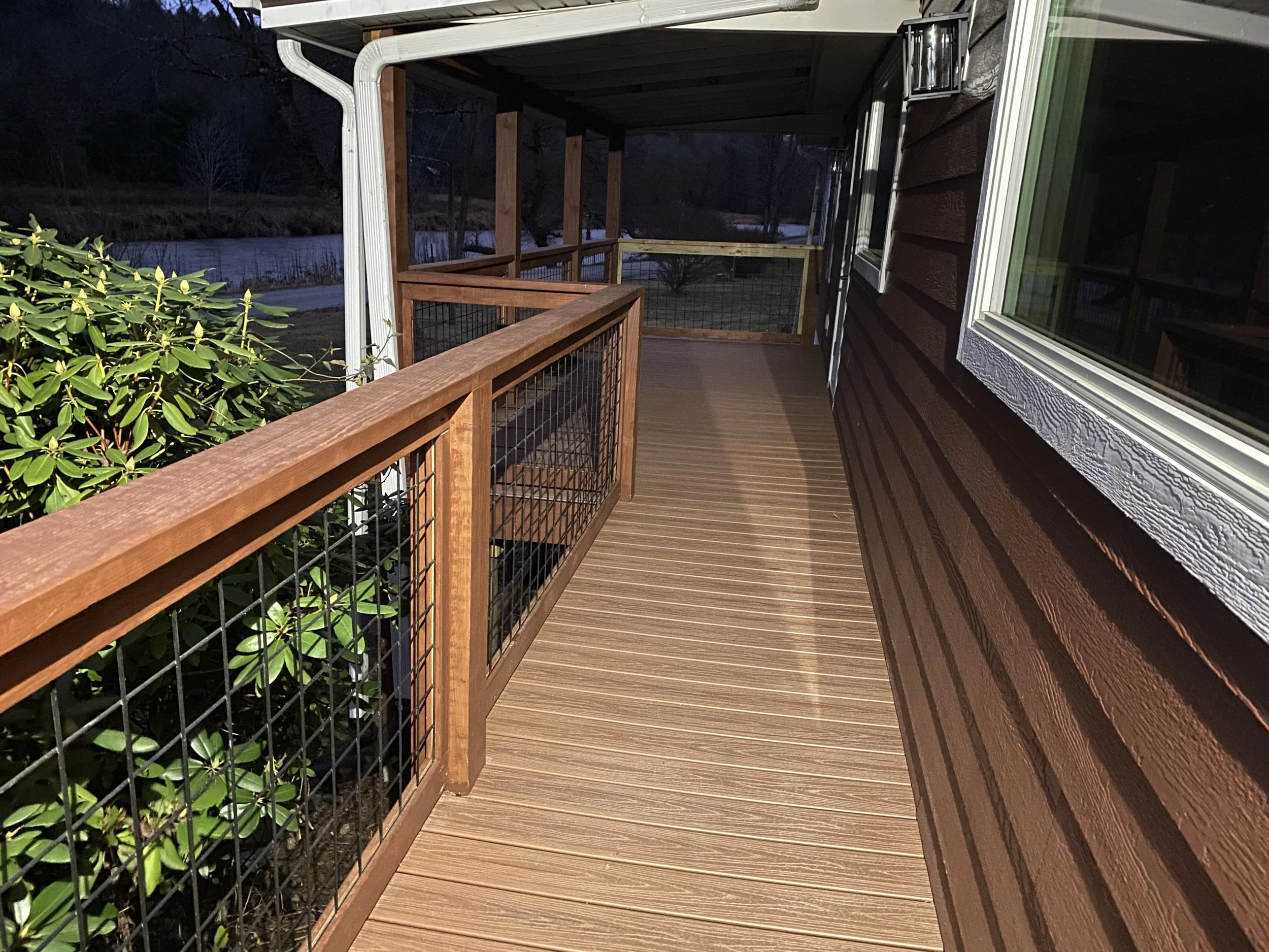 Wooden porch with a railing, attached to a house with brown siding by Antonio’s Construction providing exterior construction in Ashe County and Watauga County, NC