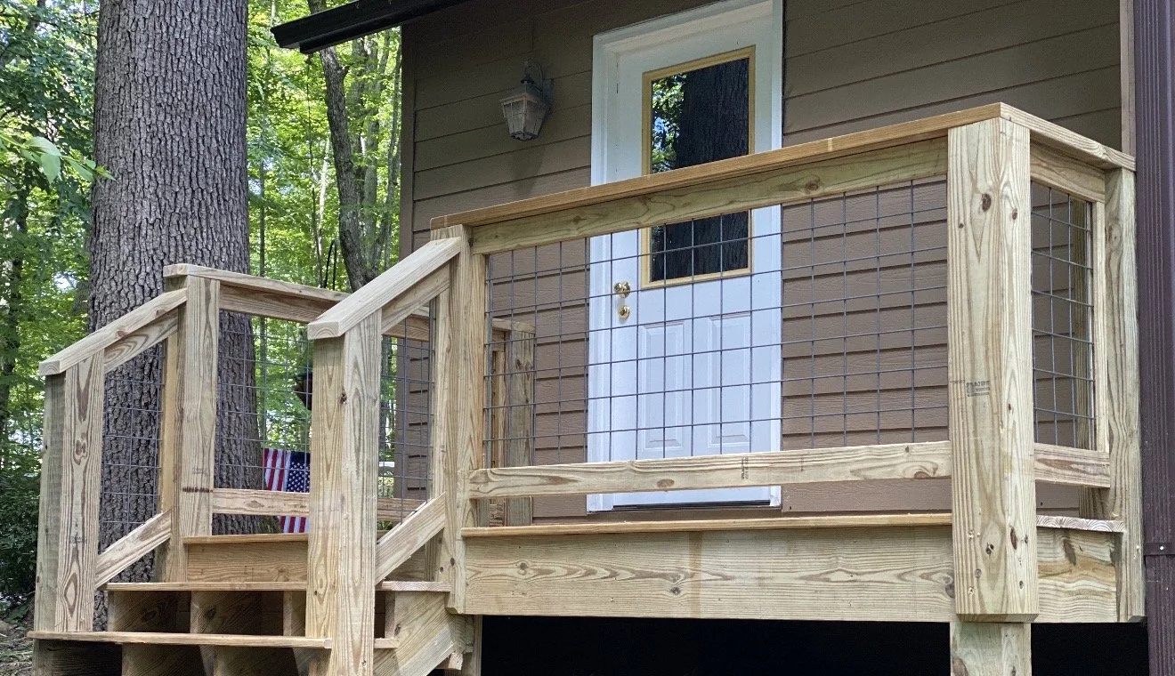 A newly built wooden deck with a railing by Antonio's Construction serving Ashe and Watauga County in North Carolina.