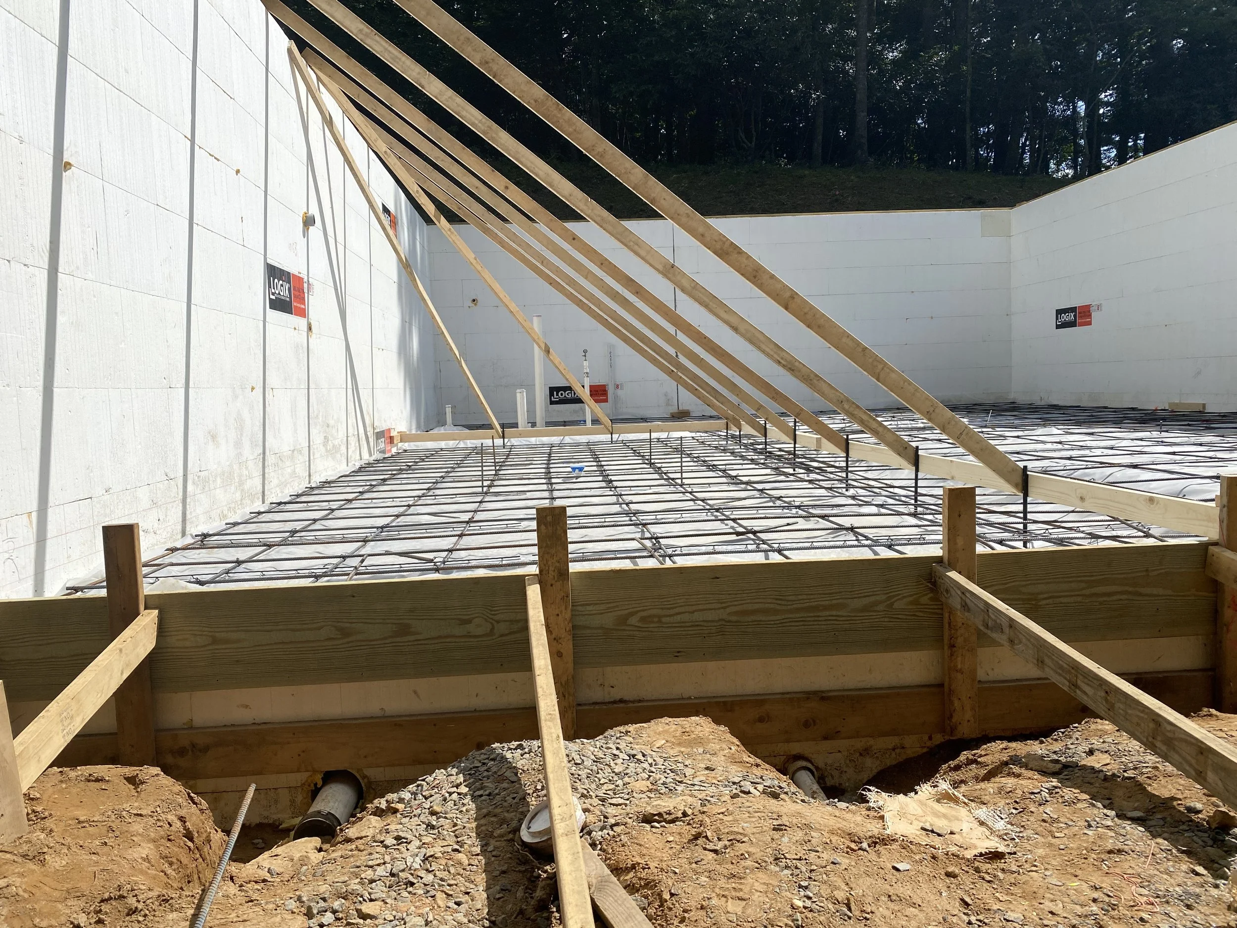 Construction site with a building frame, wooden beams, and steel rebar for concrete by Antonio’s Construction providing exterior construction in Ashe County and Watauga County, NC