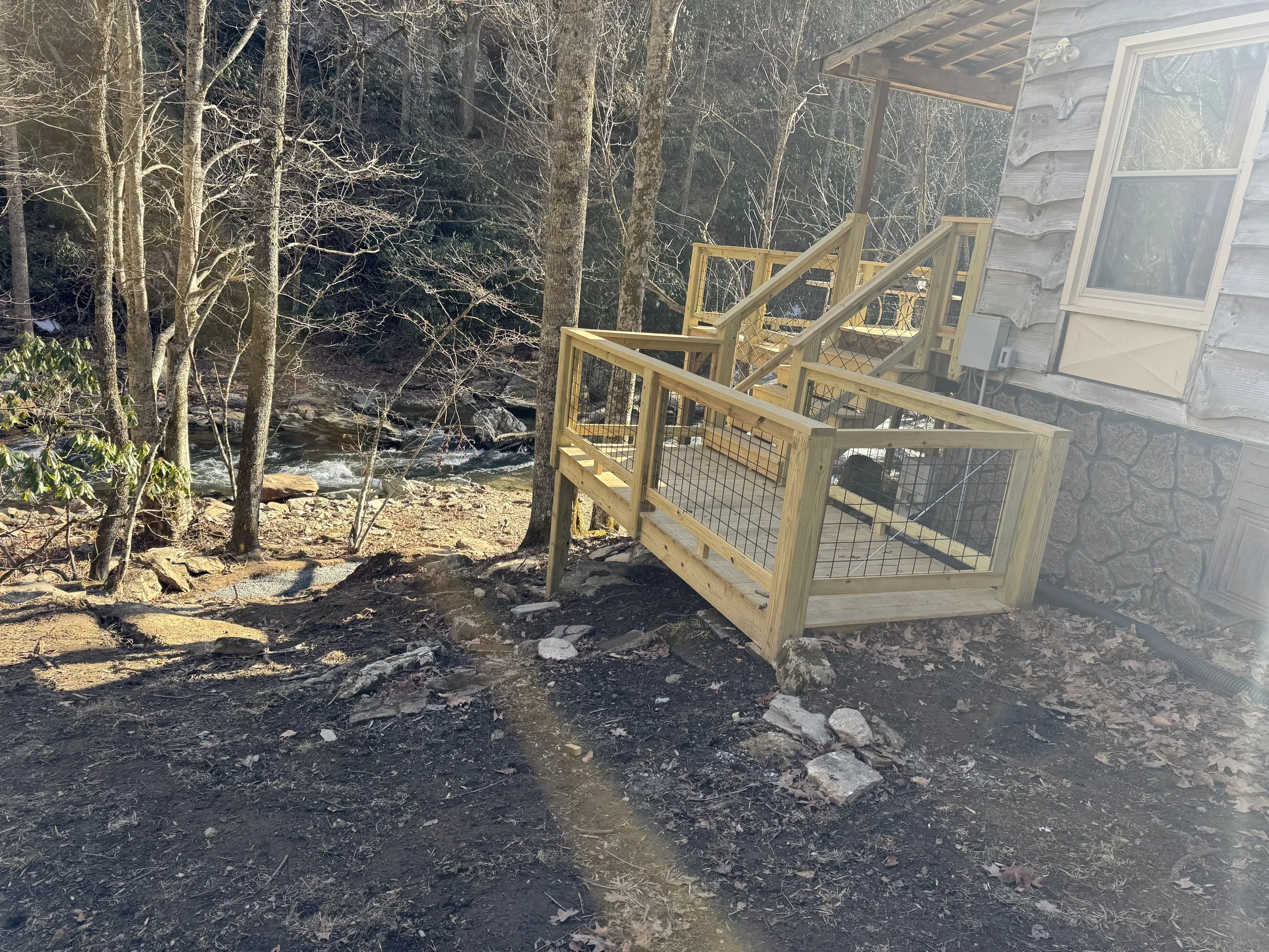 Wooden deck with lattice railing attached to a rustic house by Antonio’s Construction providing exterior construction in Ashe County and Watauga County, NC