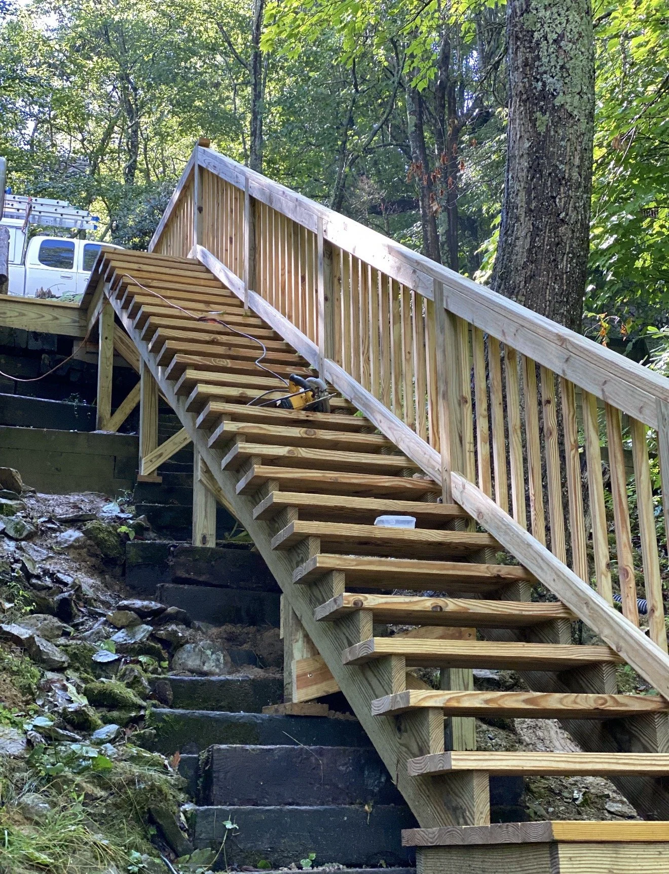 Wooden staircase with a railing by Antonio's Construction serving Ashe and Watauga County in North Carolina.