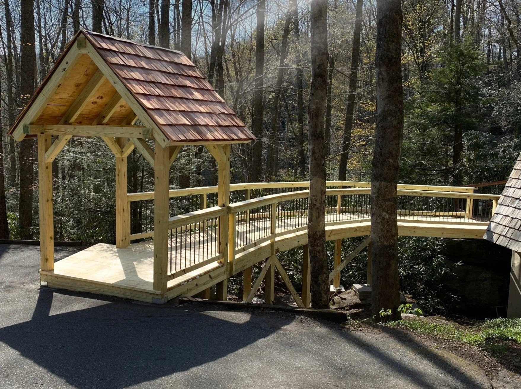 A wooden gazebo with a red shingled roof and railing by Antonio's Construction serving Ashe and Watauga County in North Carolina.