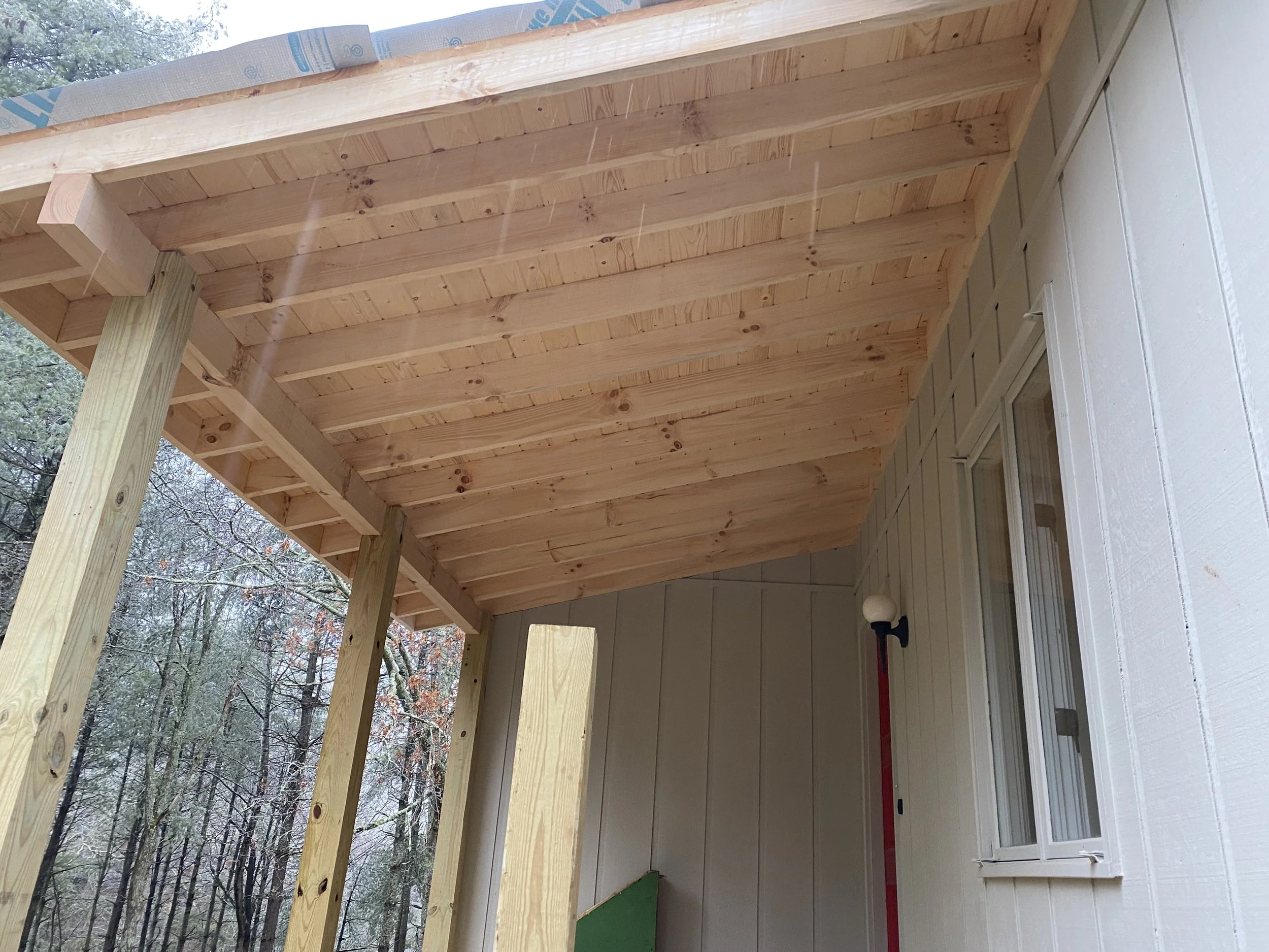 Construction of a new wooden porch with a roof extension on the side of a house, by Antonio’s Construction providing exterior construction in Ashe County and Watauga County, NC