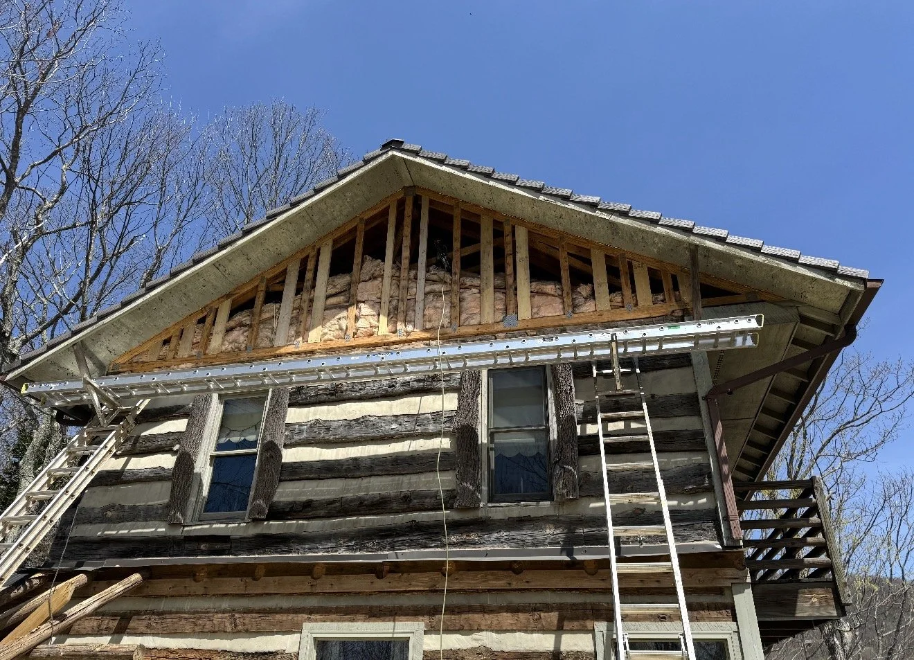 The front of a house under renovation with exposed wooden framing and insulation on the upper floor by Antonio's Construction serving Ashe and Watauga County in North Carolina.