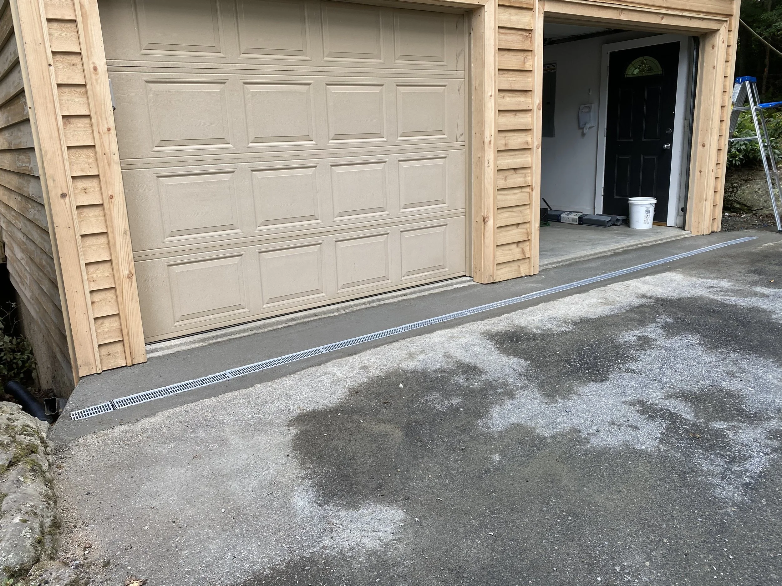 A newly built garage with a beige roll-up door by Antonio’s Construction providing exterior construction in Ashe County and Watauga County, NC