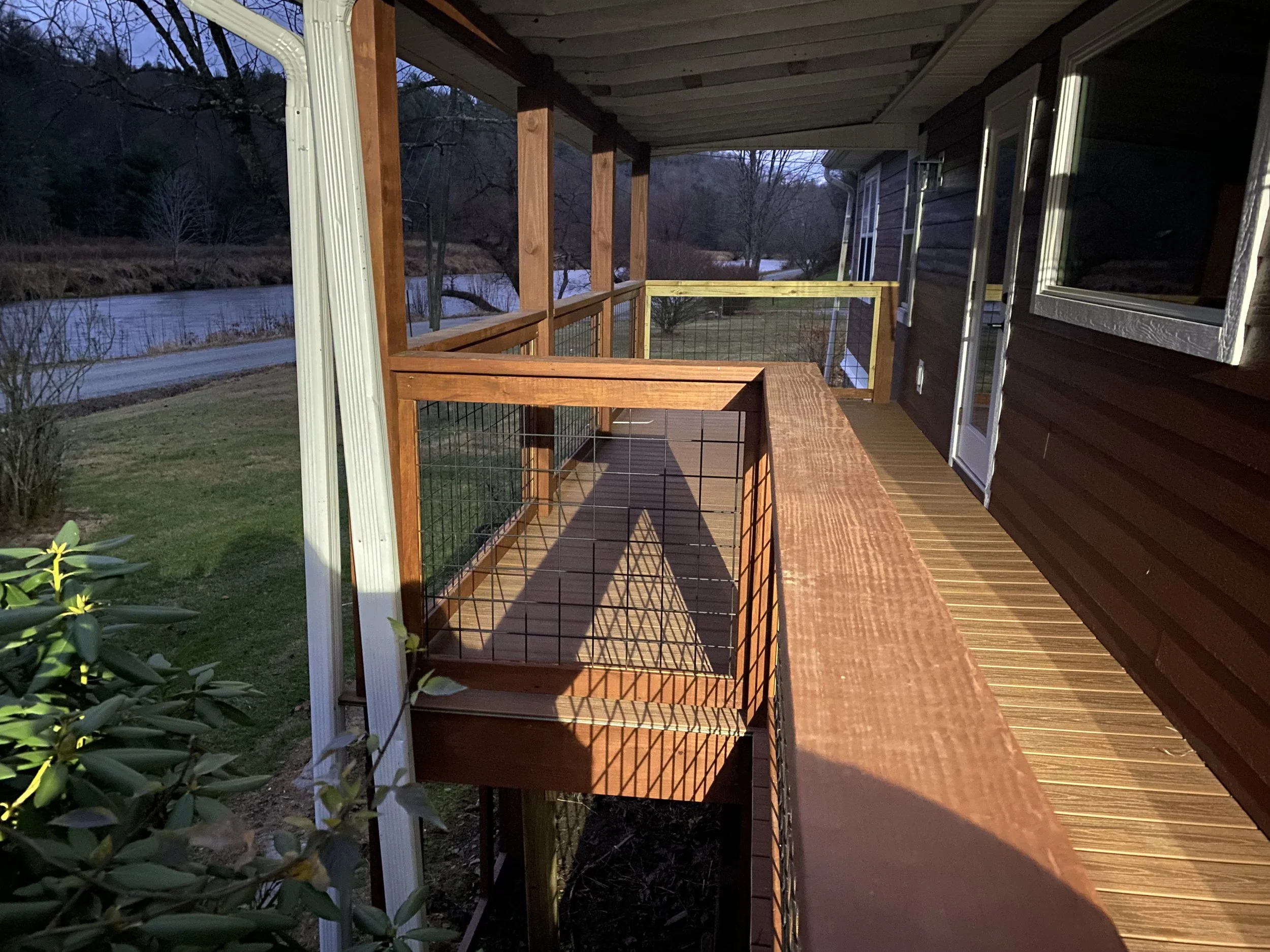 A wooden deck with a railing, attached to a house, built by Antonio’s Construction providing exterior construction in Ashe County and Watauga County, NC