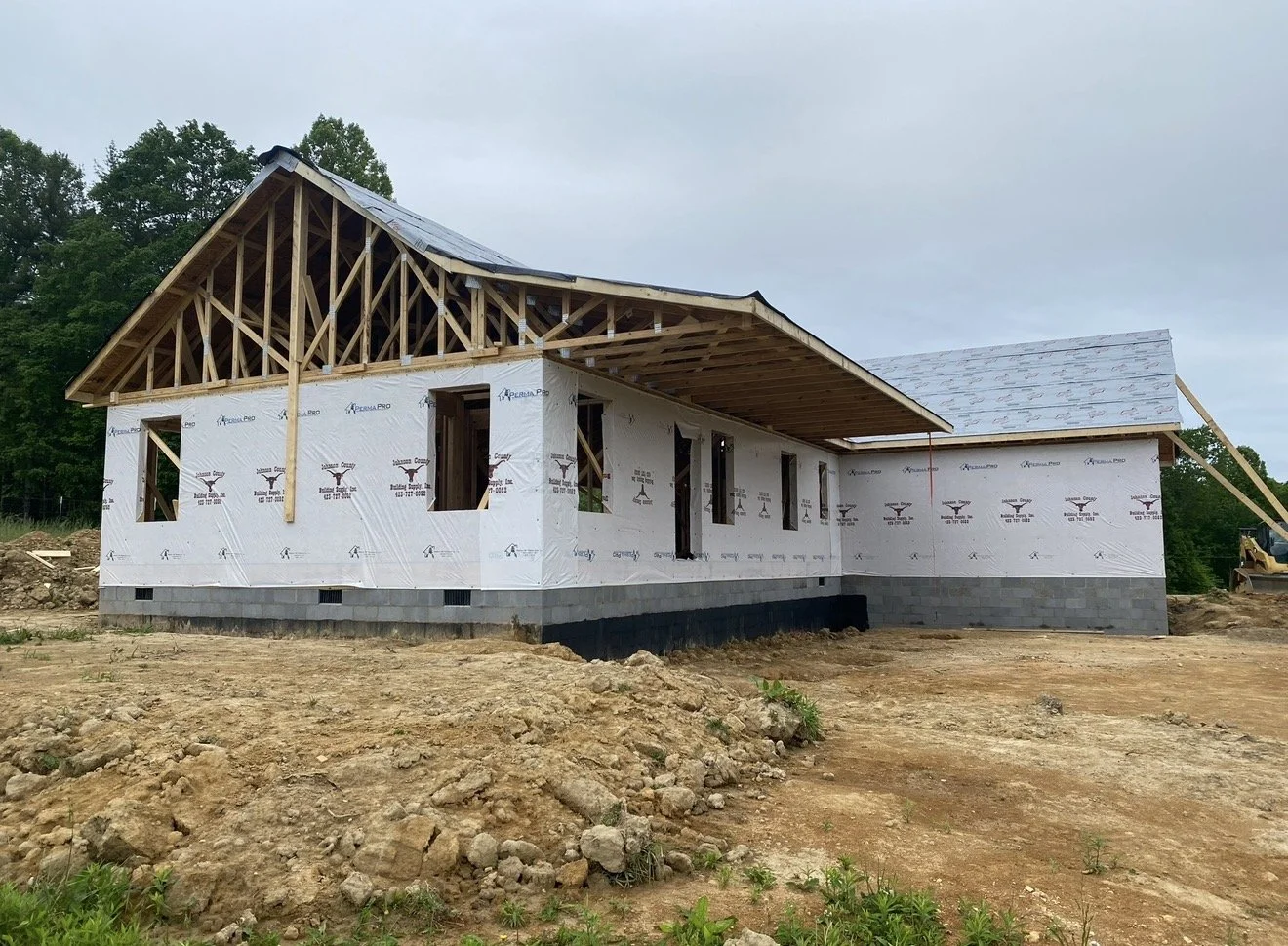 A house under construction with a wooden framework and white weather-resistant sheathing Antonio's Construction serving Ashe and Watauga County in North Carolina.