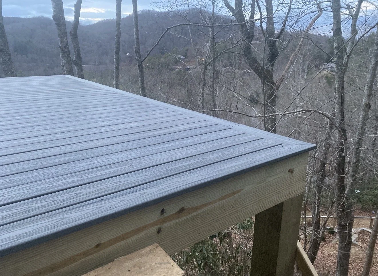 Close-up of a wooden deck corner with gray painted siding by Antonio's Construction serving Ashe and Watauga County in North Carolina.