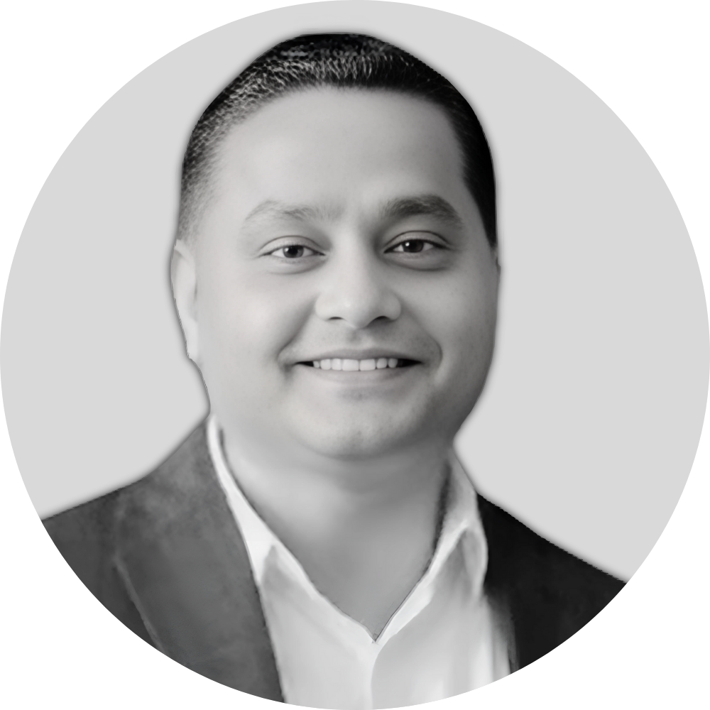 Black and white headshot of a smiling man in formal attire with a suit jacket and white shirt.