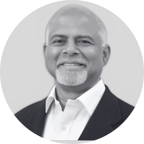 Black and white portrait of a man with short gray hair and a beard, wearing a suit jacket and white shirt.
