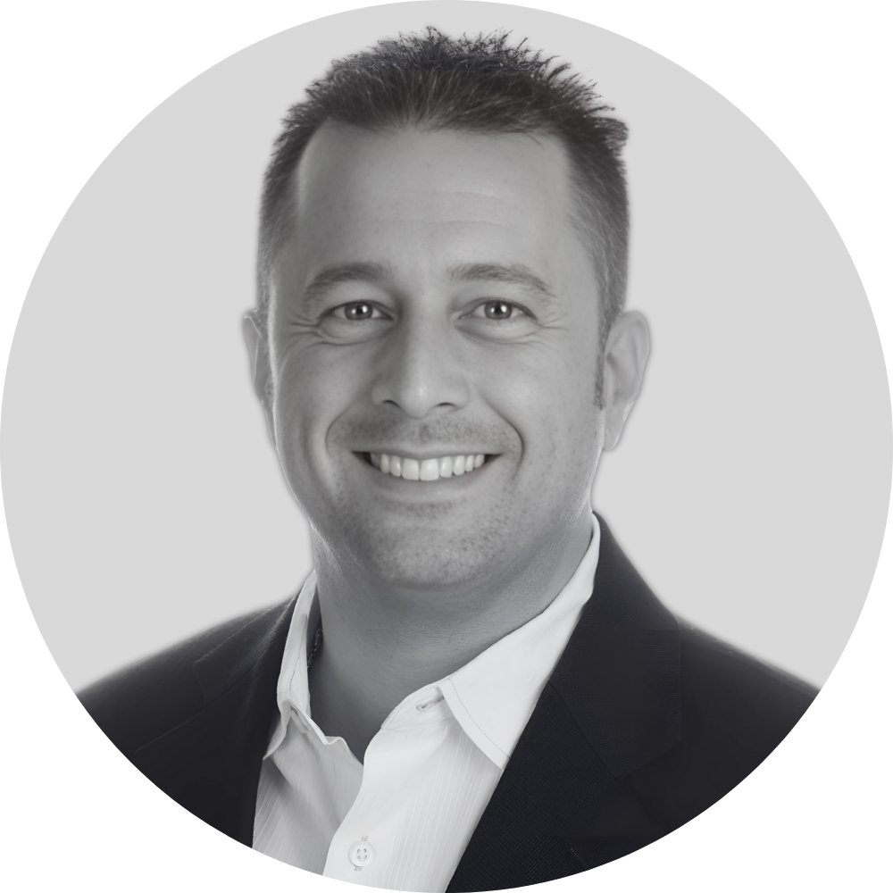 Black and white professional headshot of a smiling man wearing a suit and white shirt.