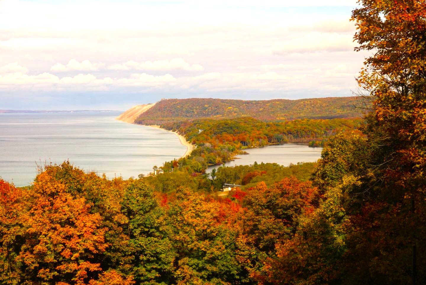 Autumn landscape with colorful fall foliage, a body of water, and hills in the distance.