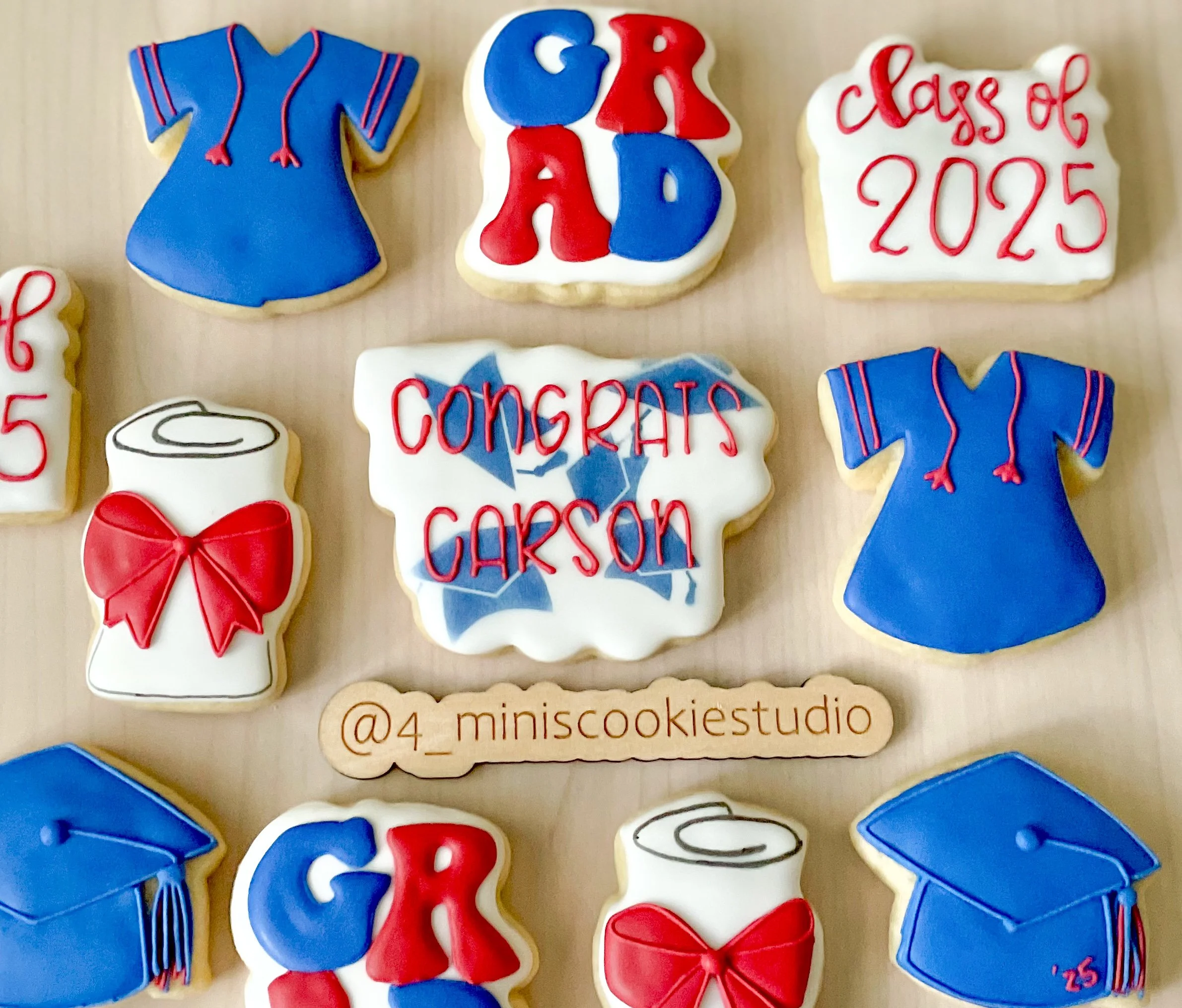 Assorted decorated cookies for a graduation celebration, featuring messages like "GRA D," "Congrats Garson," and "Class of 2025," along with cookie shaped and decorated as graduation caps, a gown, a diploma, and a blood type badge, all in red, blue, 