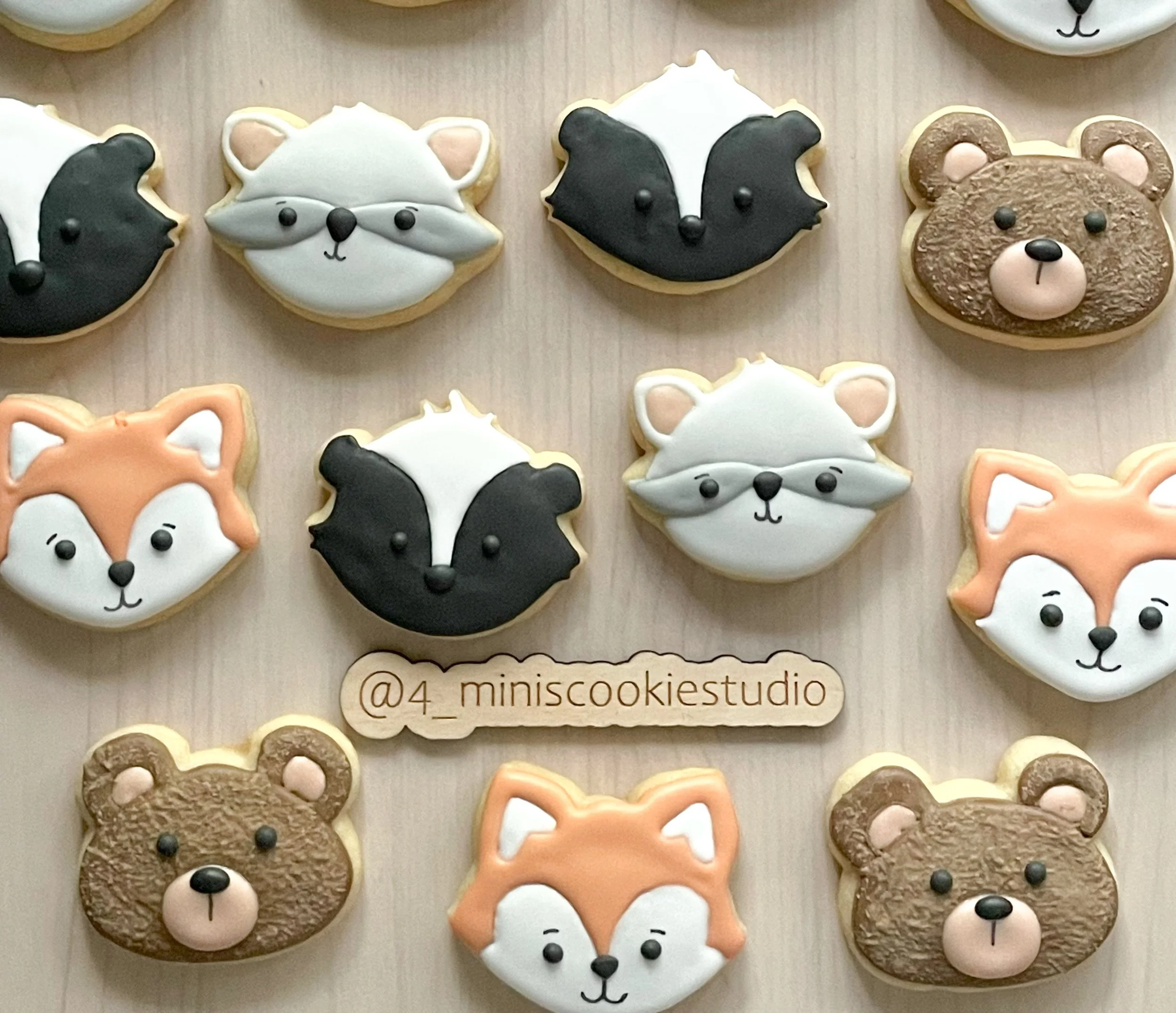 Collection of animal-shaped decorated cookies featuring foxes, raccoons, and bears.