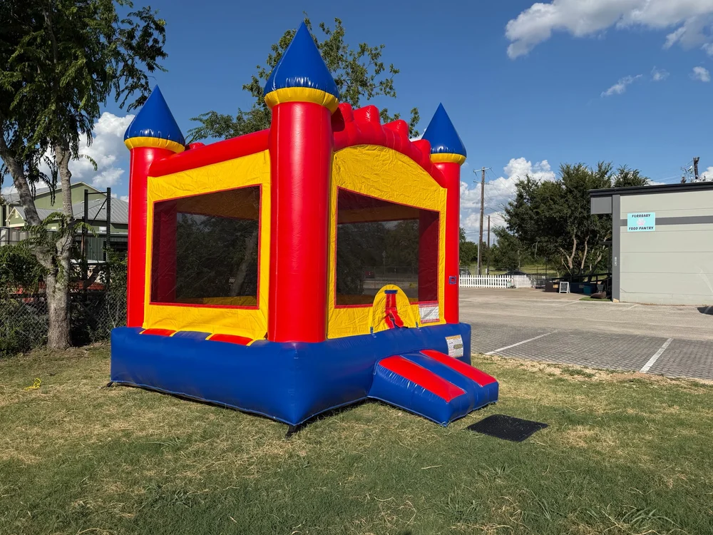 Red, yellow and blue Castle Bounce House set up outdoors by Hill Country Celebration Rentals