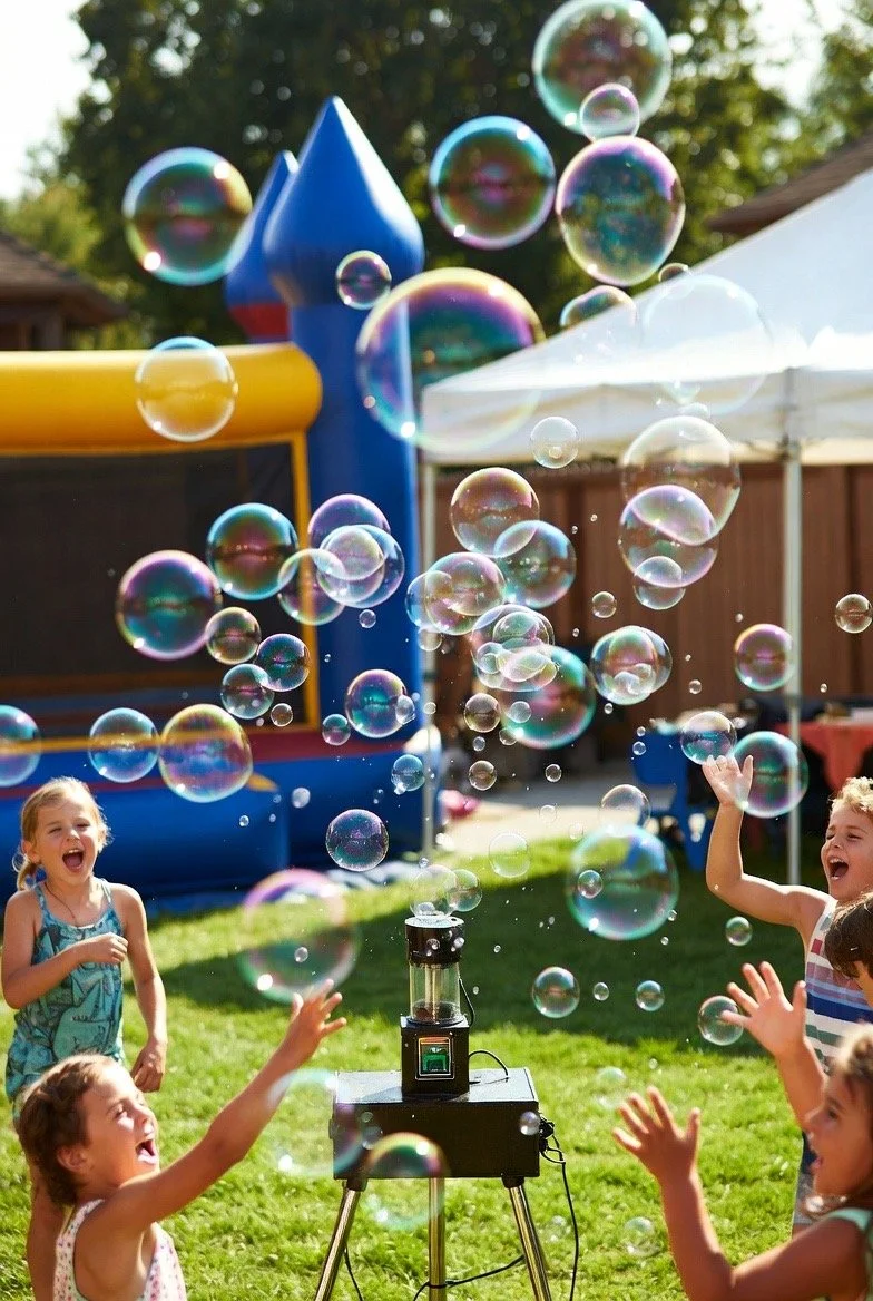 Kids playing with soap bubbles outdoors in a backyard, with a bounce house and a canopy in the background.