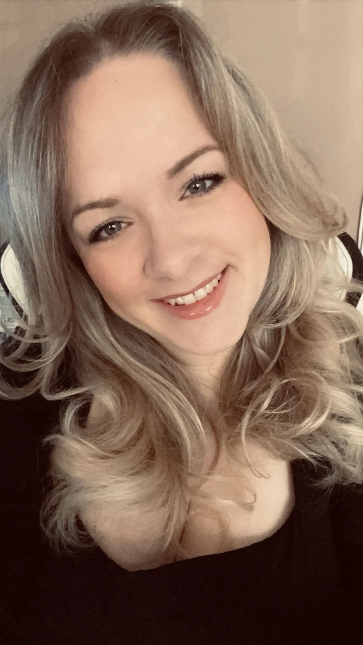 A woman with long, curly blonde hair smiling at the camera.