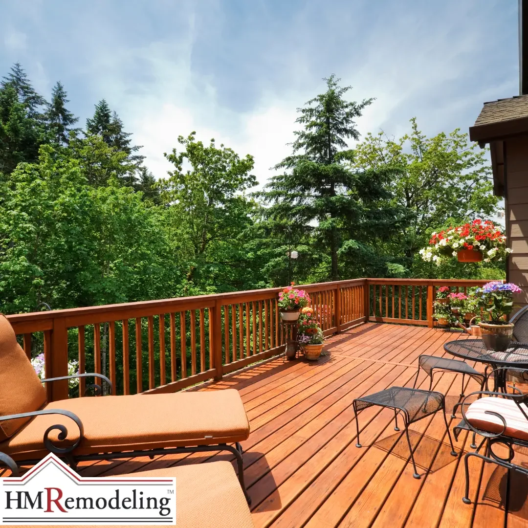 A wood deck with a matching wood railing, cushioned patio furniture, and hanging flower baskets overlooking trees at a South Bend, Indiana home.