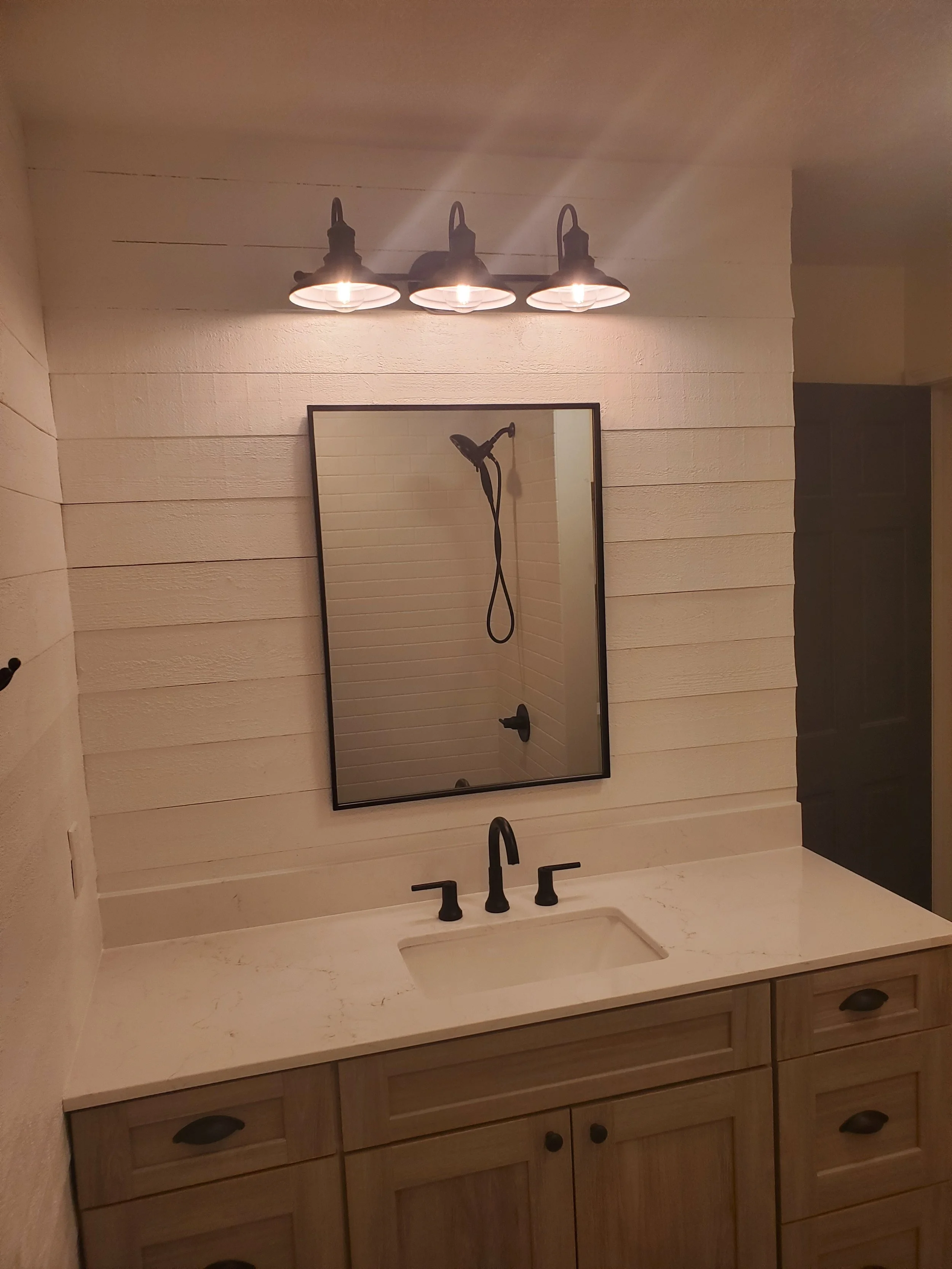 HM Remodeling farmhouse bathroom with sconce lighting shiplap and vanity in South Bend Indiana