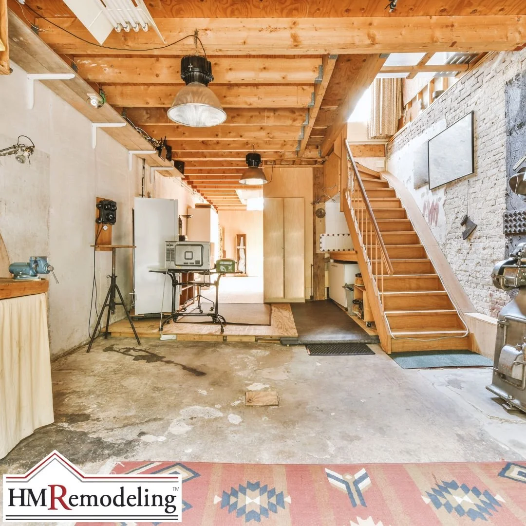 Unfinished South Bend basement with bare concrete floor, exposed wood beam ceiling, brick foundation wall, and open staircase illustrating the importance of moisture assessment before basement finishing in Northern Indiana