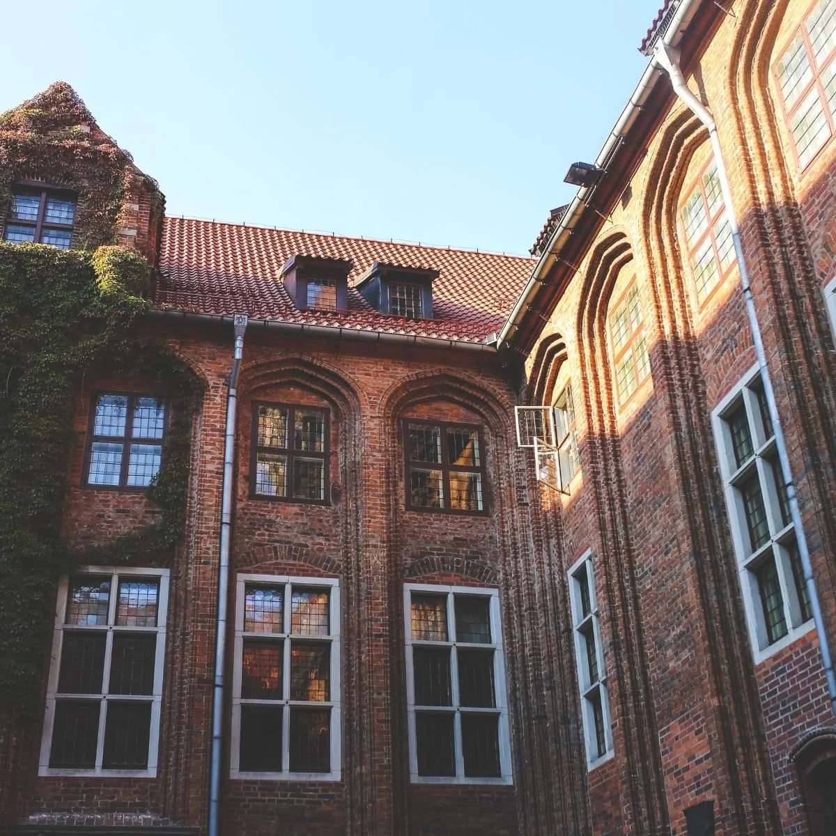 Two-story older home exterior with cream lap siding, covered front porch with columns, upper balcony, wood entry door, and hip roof representing exterior modernization in South Bend and Michiana