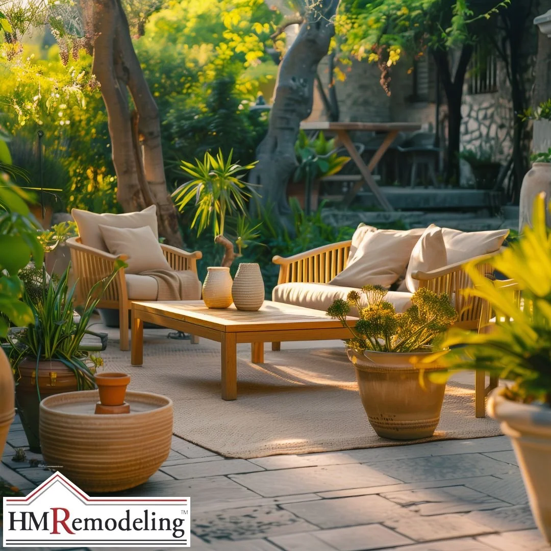 Outdoor stone patio with wicker sectional sofa, orange accent chairs, glass coffee table, and wood horizontal privacy fence surrounded by mature trees in a South Bend, Indiana backyard