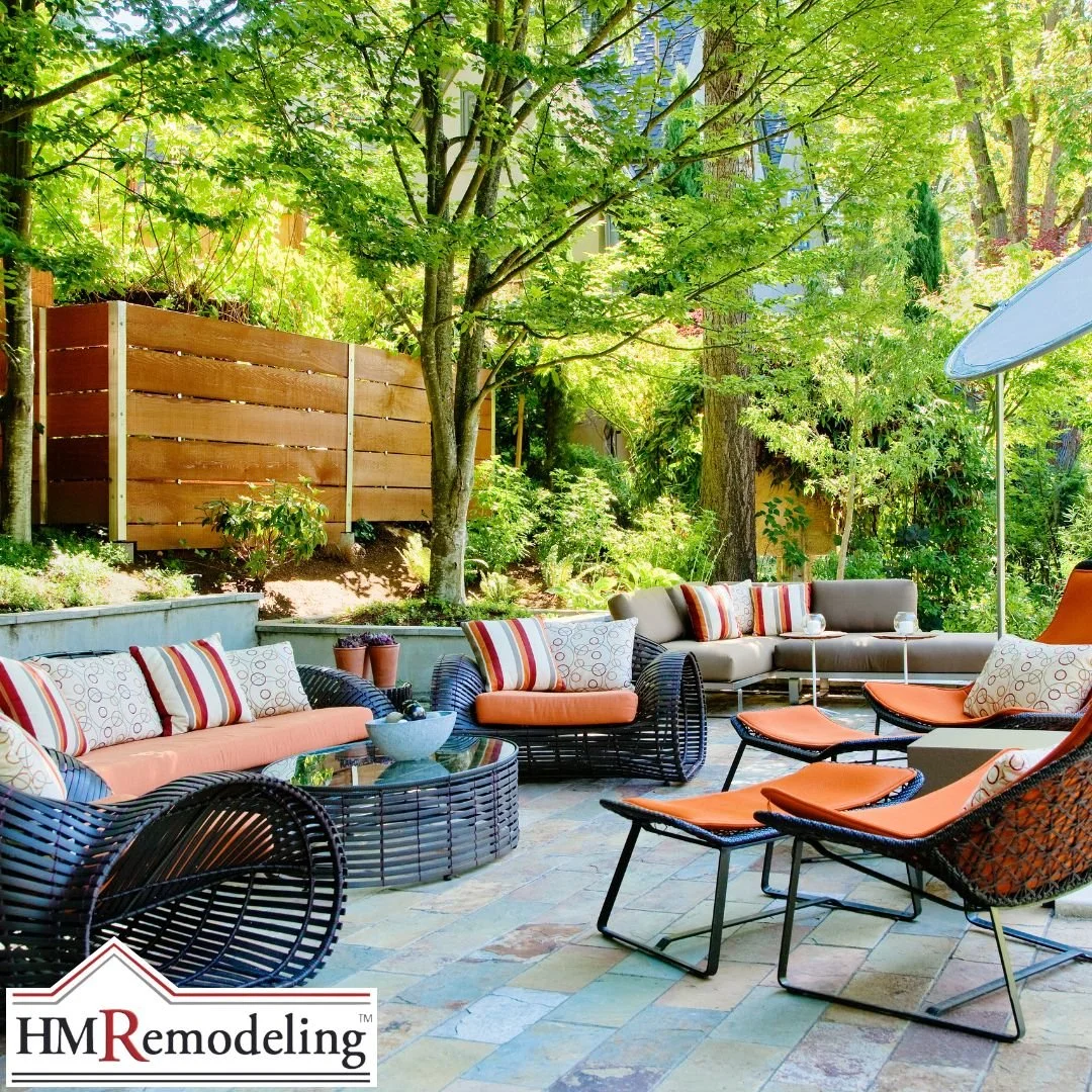 Teak outdoor sofa and lounge chairs on stone paver patio with woven coffee table, ceramic planters, and lush summer garden plantings in a South Bend, Indiana outdoor living space