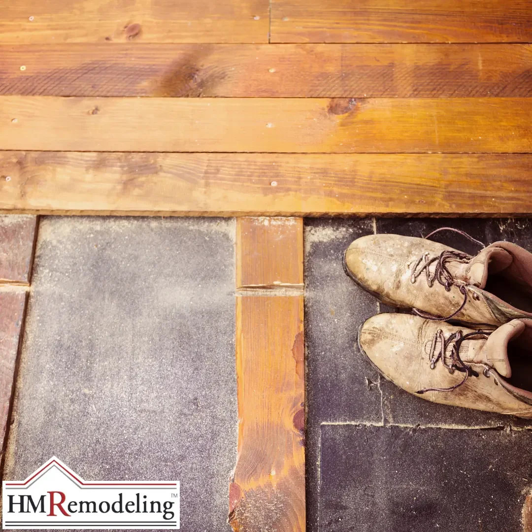 A close-up of a deteriorated entry floor threshold in a South Bend, Indiana home showing salt-stained and worn tile alongside warped wood planks, with a pair of heavily salt-dusted winter boots resting on the surface