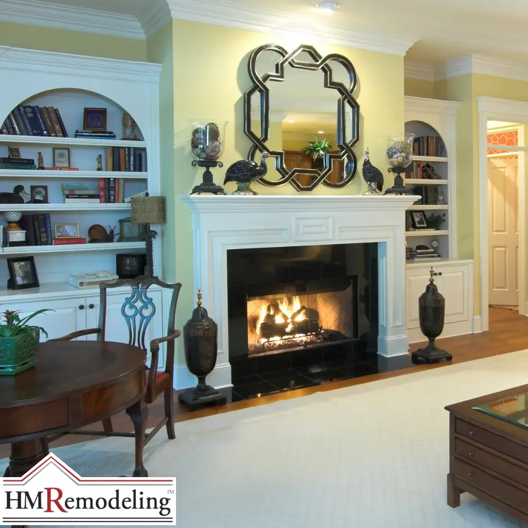 A traditional living room in a South Bend, Indiana home featuring a white wood-burning fireplace surround with flanking arched built-in bookshelves filled with books and decorative objects, crown molding, and green walls