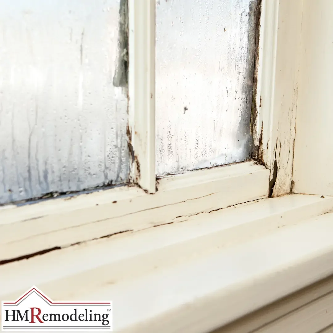 A close-up of an old painted window frame and sill with cracked, peeling paint, rot, and moisture staining in a South Bend, Indiana home.
